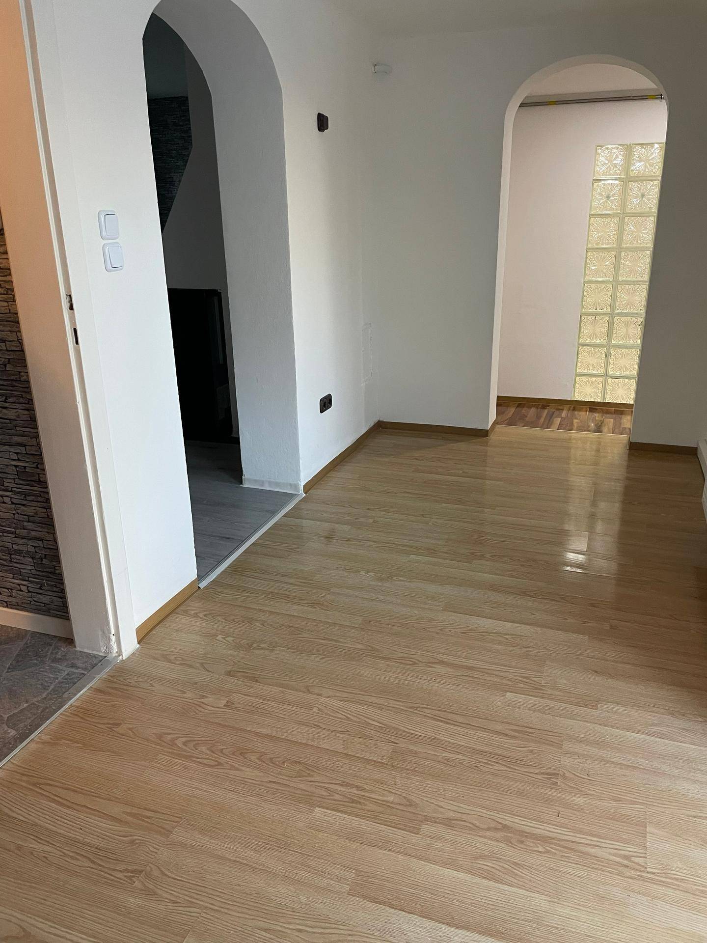 Geräumiger Flur mit hellen Laminatböden, eleganten Rundbögen und einer dekorativen Glasbausteinwand.