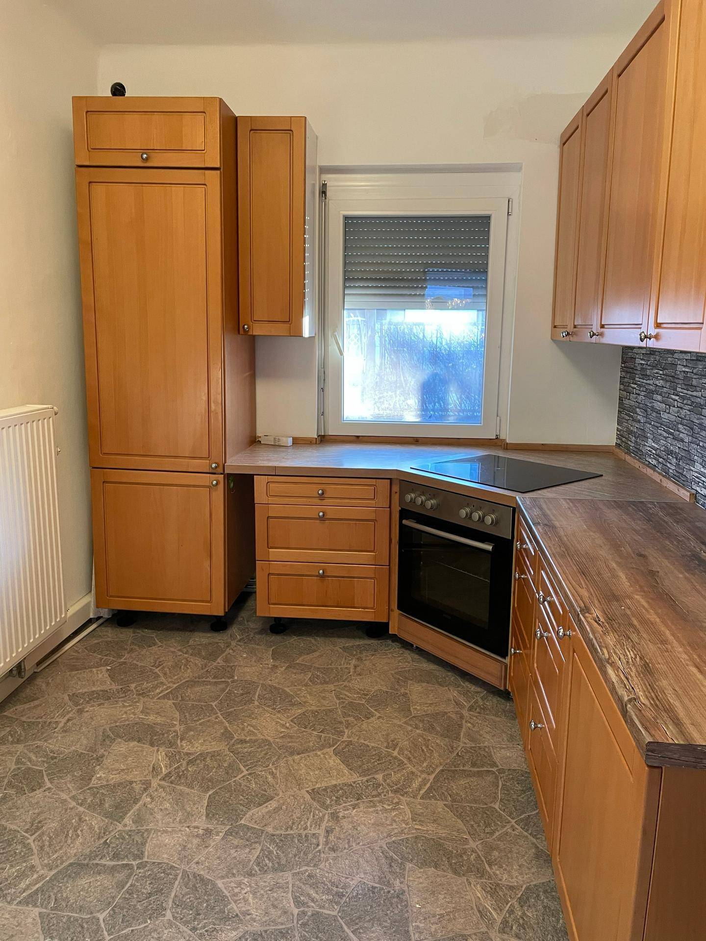 Funktionale Küche mit hellen Holzschränken, integriertem Backofen und Induktionskochfeld, bereit zur Nutzung.
