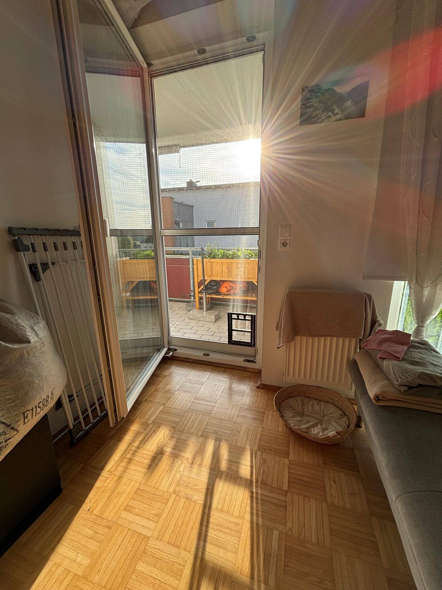 Heller Innenraum mit Parkettboden und direktem Zugang zu einem sonnigen Balkon.