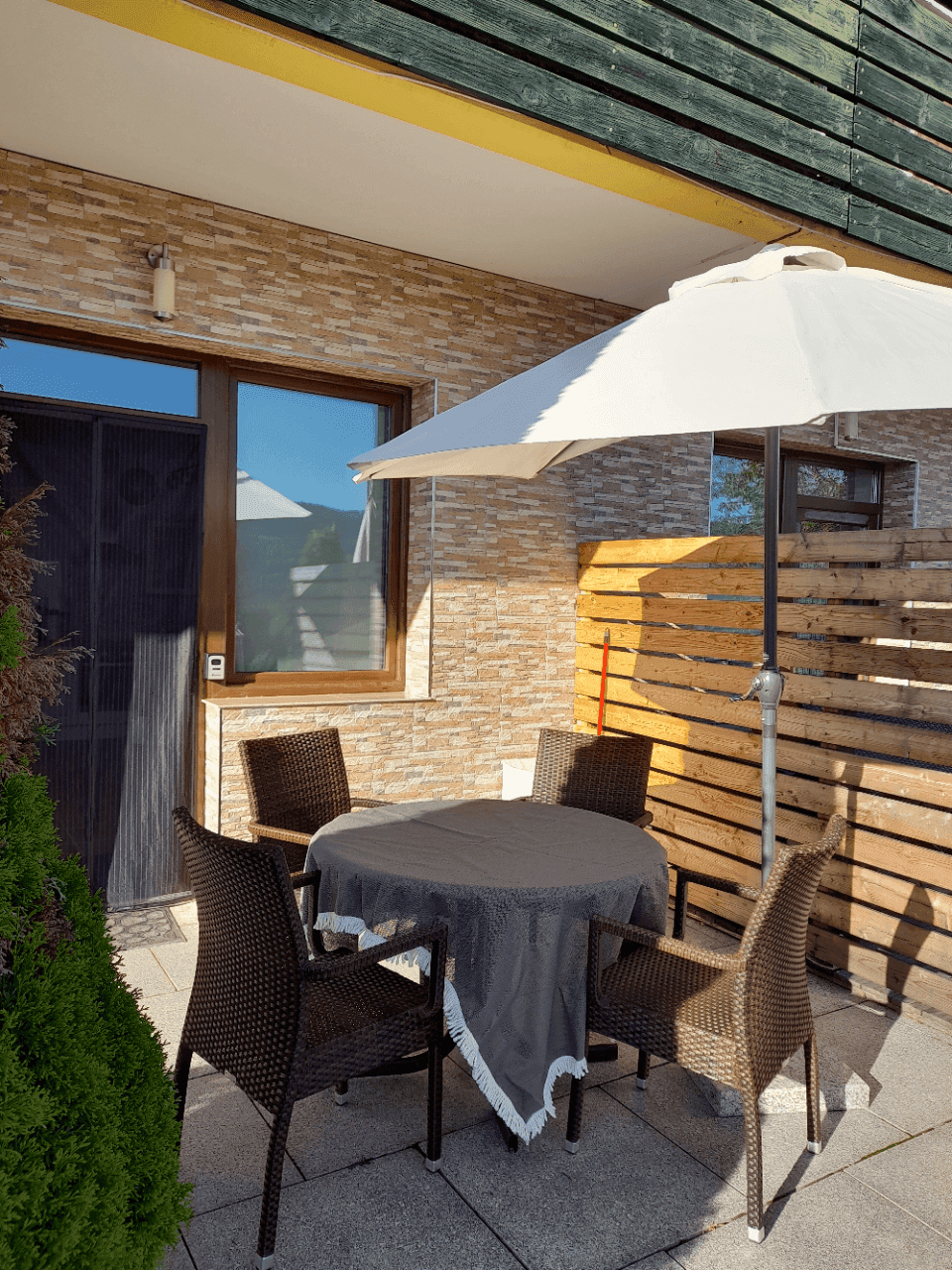 Sonnige Terrasse mit Esstisch, Stühlen und Sonnenschirm für entspannte Stunden im Freien.