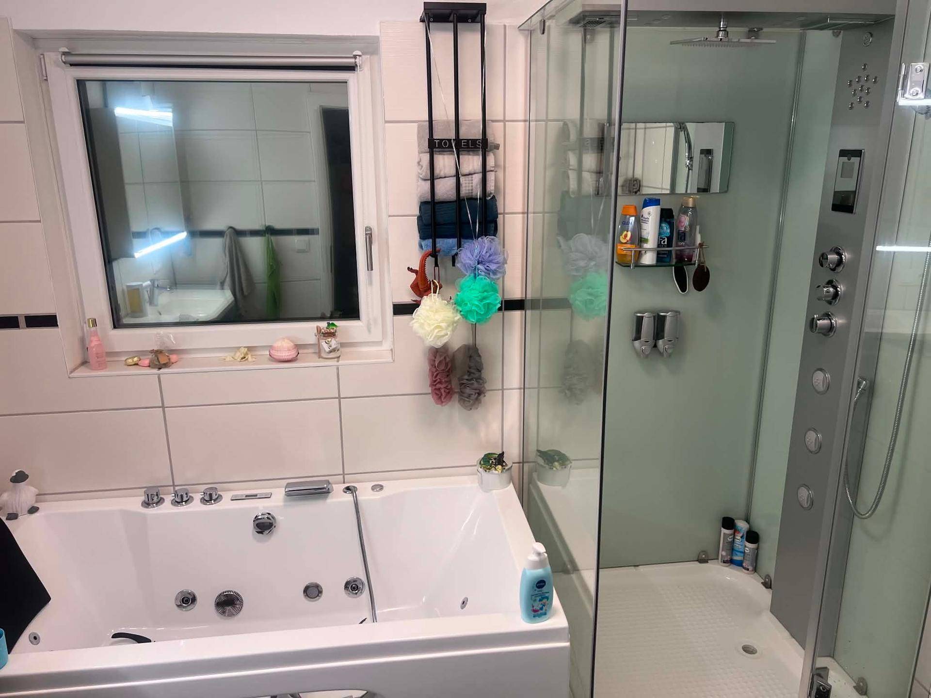 Badezimmer mit moderner Duschkabine und Badewanne mit Whirlpool-Funktion.