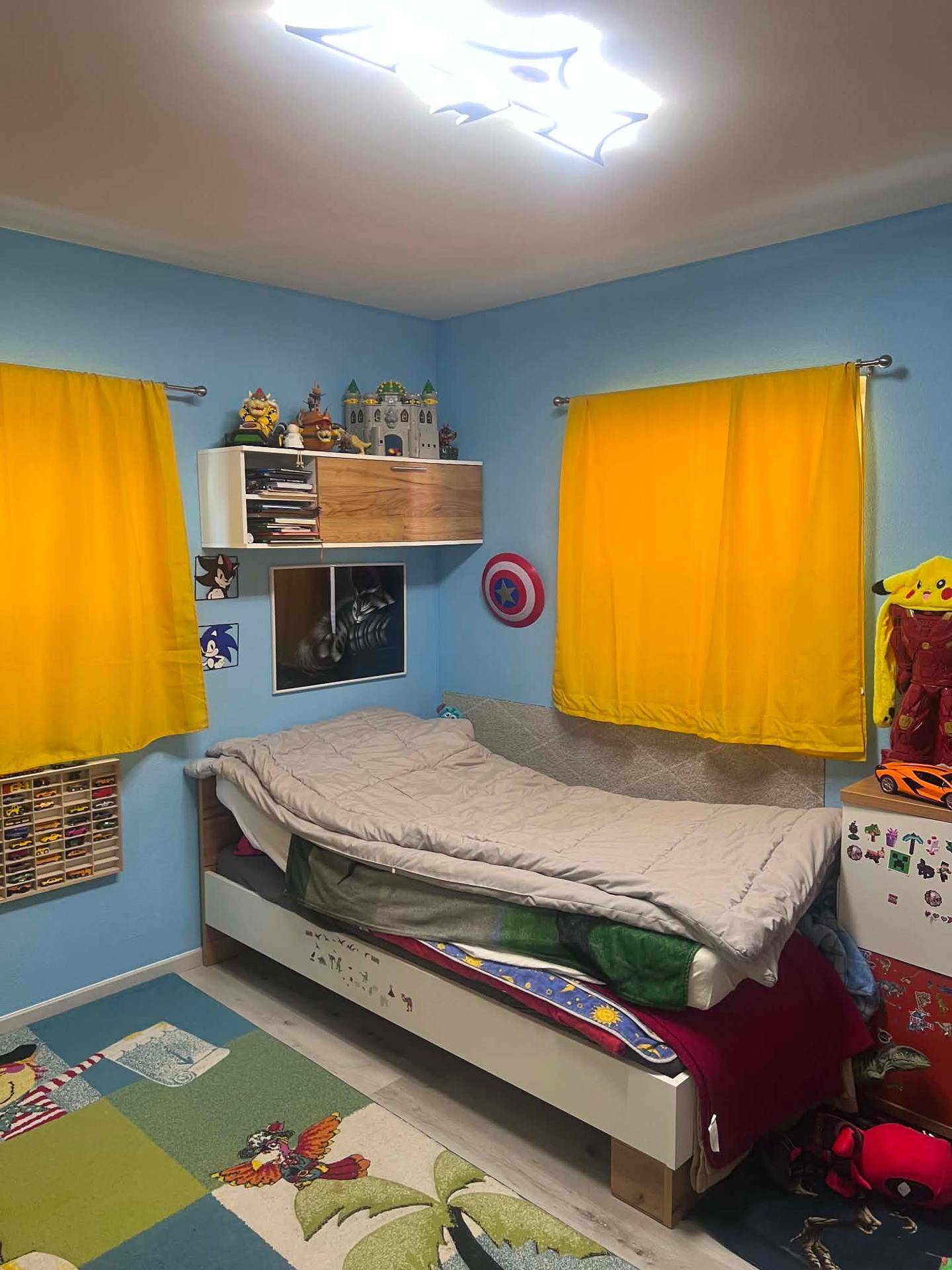 Helles Kinderzimmer mit blauen Wänden, Einzelbett und gelben Vorhängen.