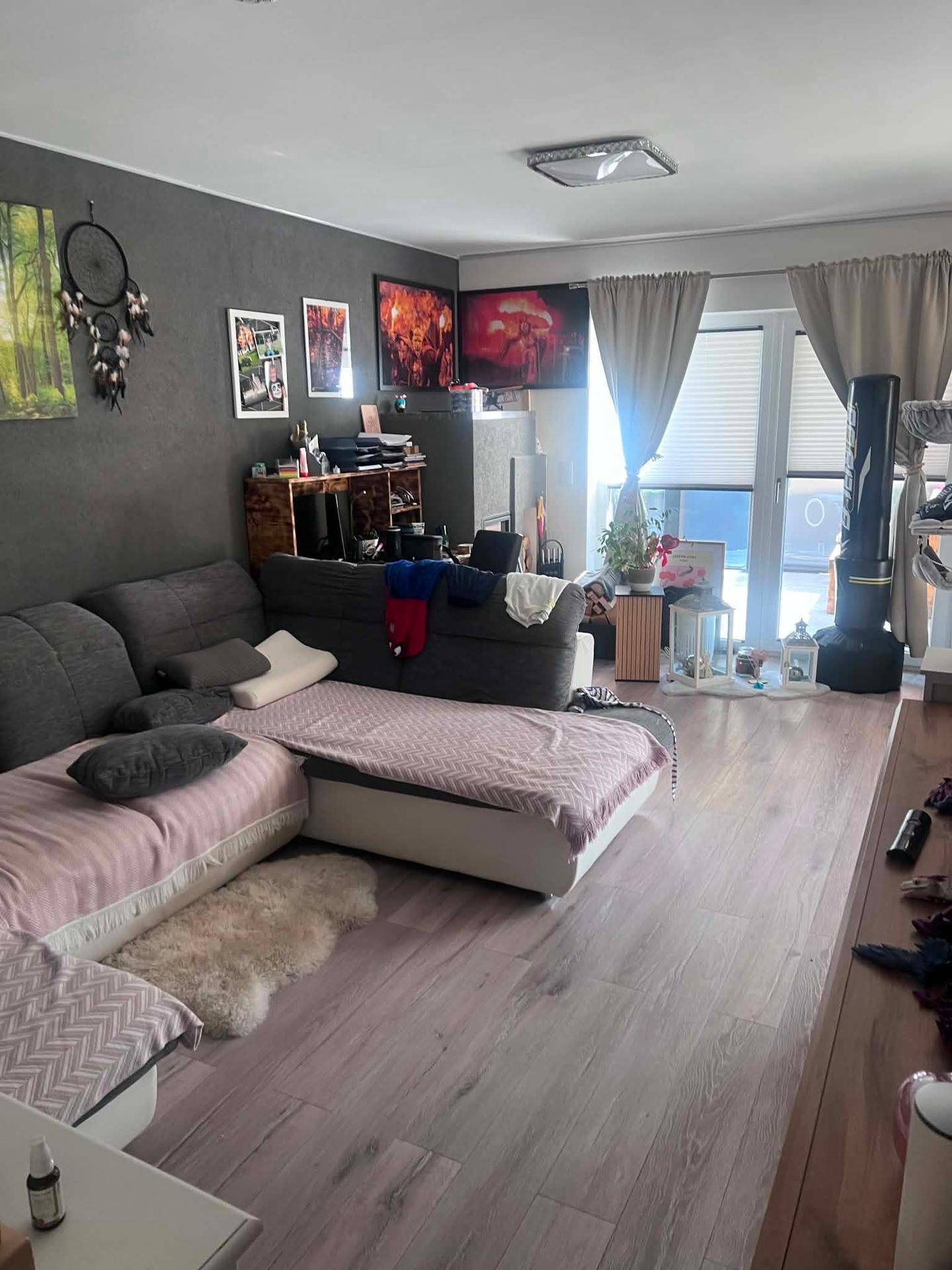Geräumiges Wohnzimmer mit großem Ecksofa, modernem Laminatboden und viel Tageslicht.