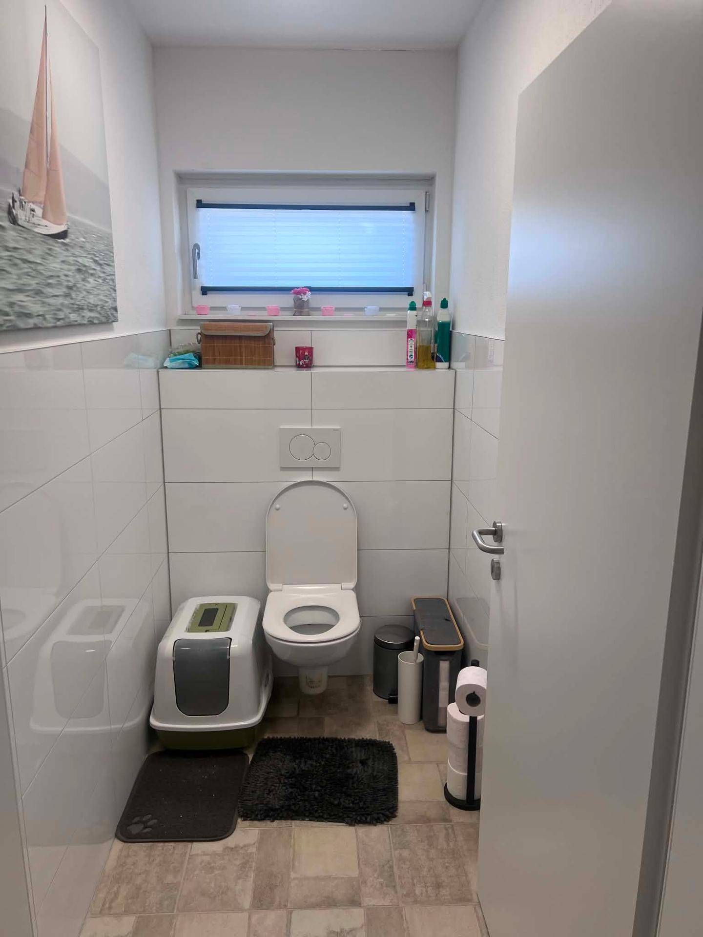 Kleines WC mit weißen Fliesen, wandhängendem WC und Fenster für Tageslicht.