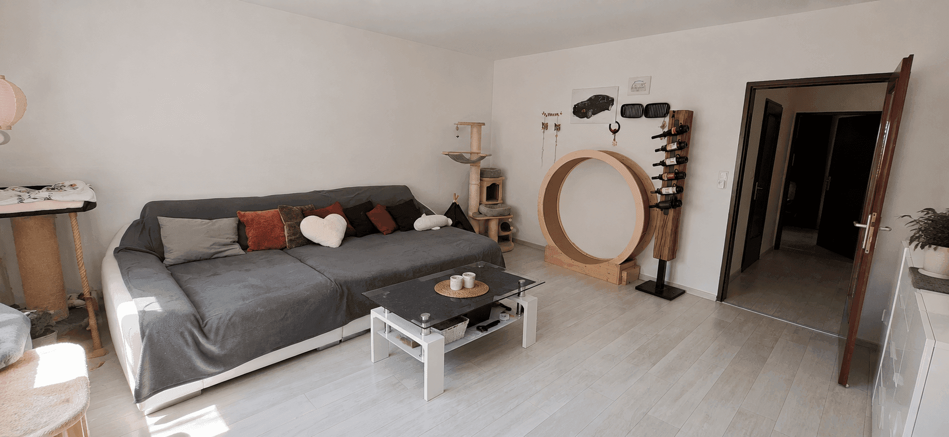 Geräumiges Wohnzimmer mit Sofa, Laminatboden und Zugang zu weiteren Räumen im Hintergrund.