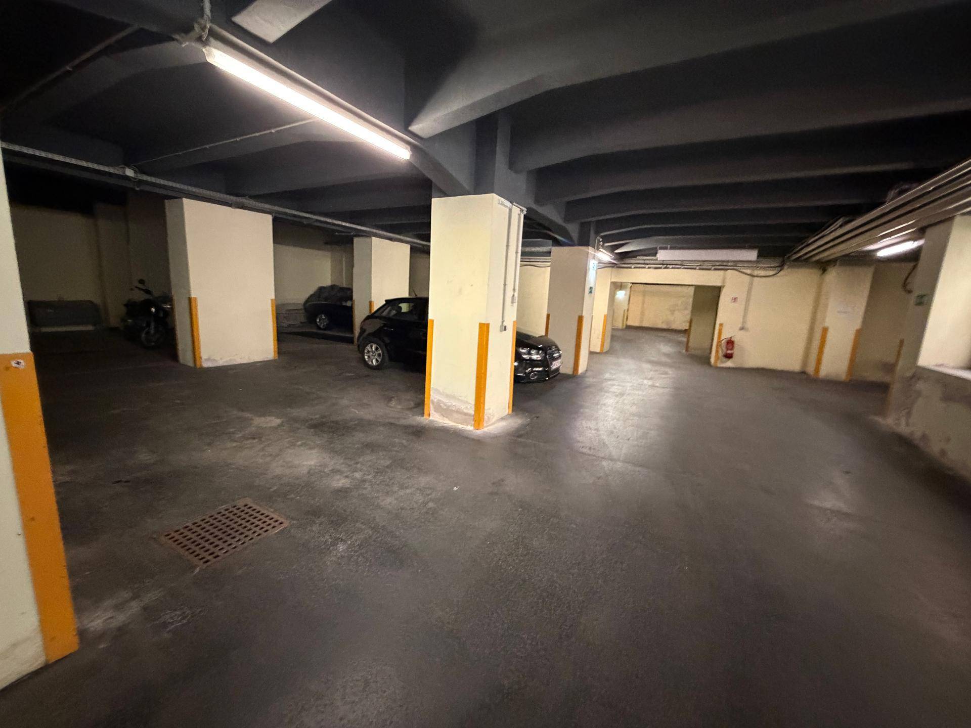 Geräumige Tiefgarage mit mehreren Stellplätzen, Betonpfeilern und Beleuchtung.