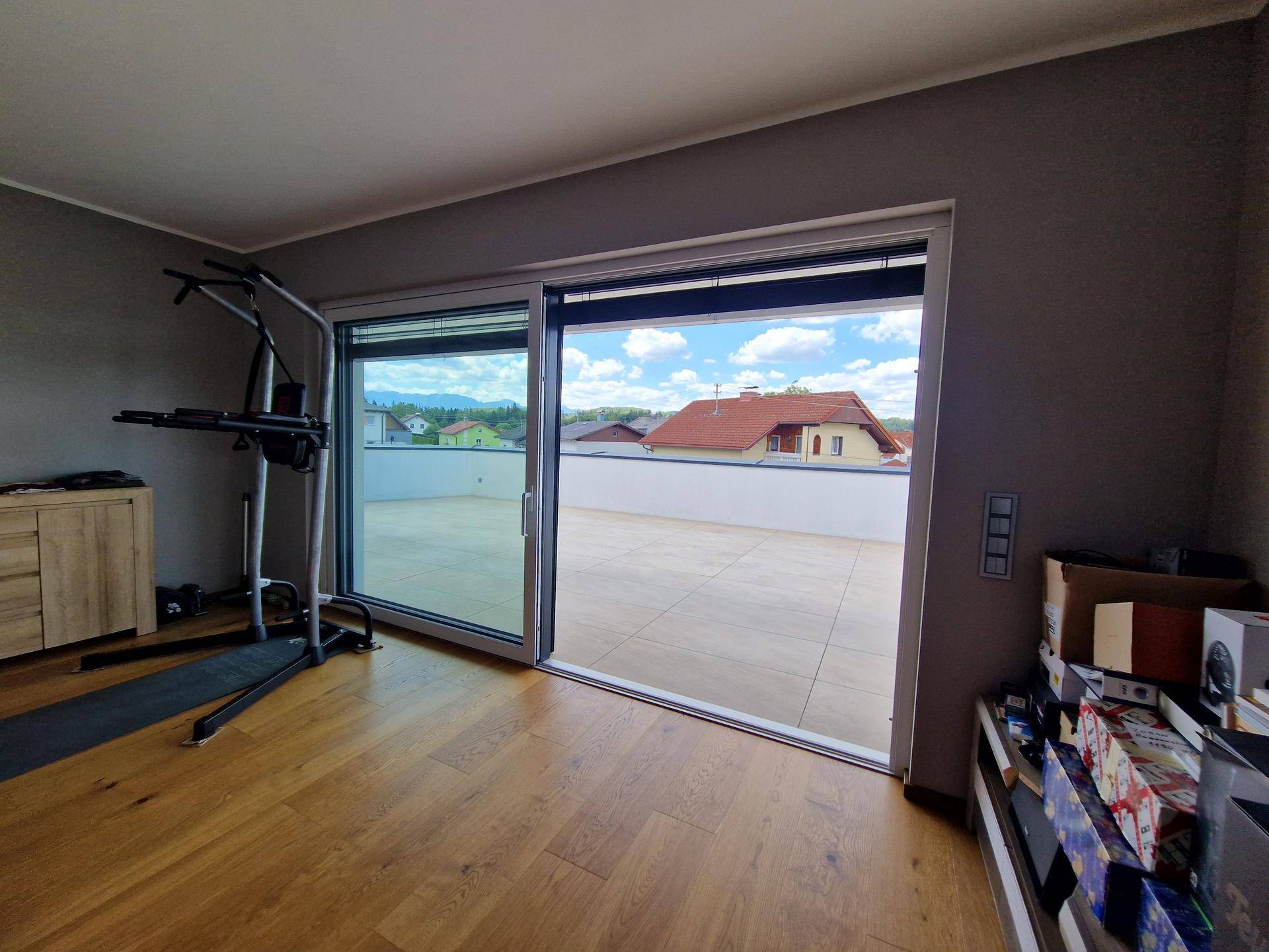 Blick vom Schlafzimmer auf die große Terrasse durch bodentiefe Schiebetüren.