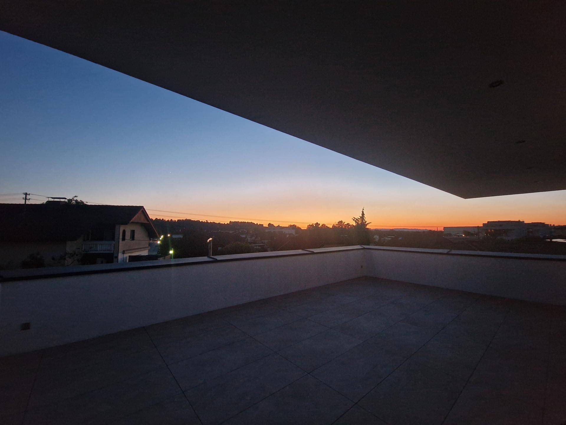 Stimmungsvoller Sonnenuntergang von der Terrasse aus, der den Himmel in warmen Orange- und Blautönen färbt.