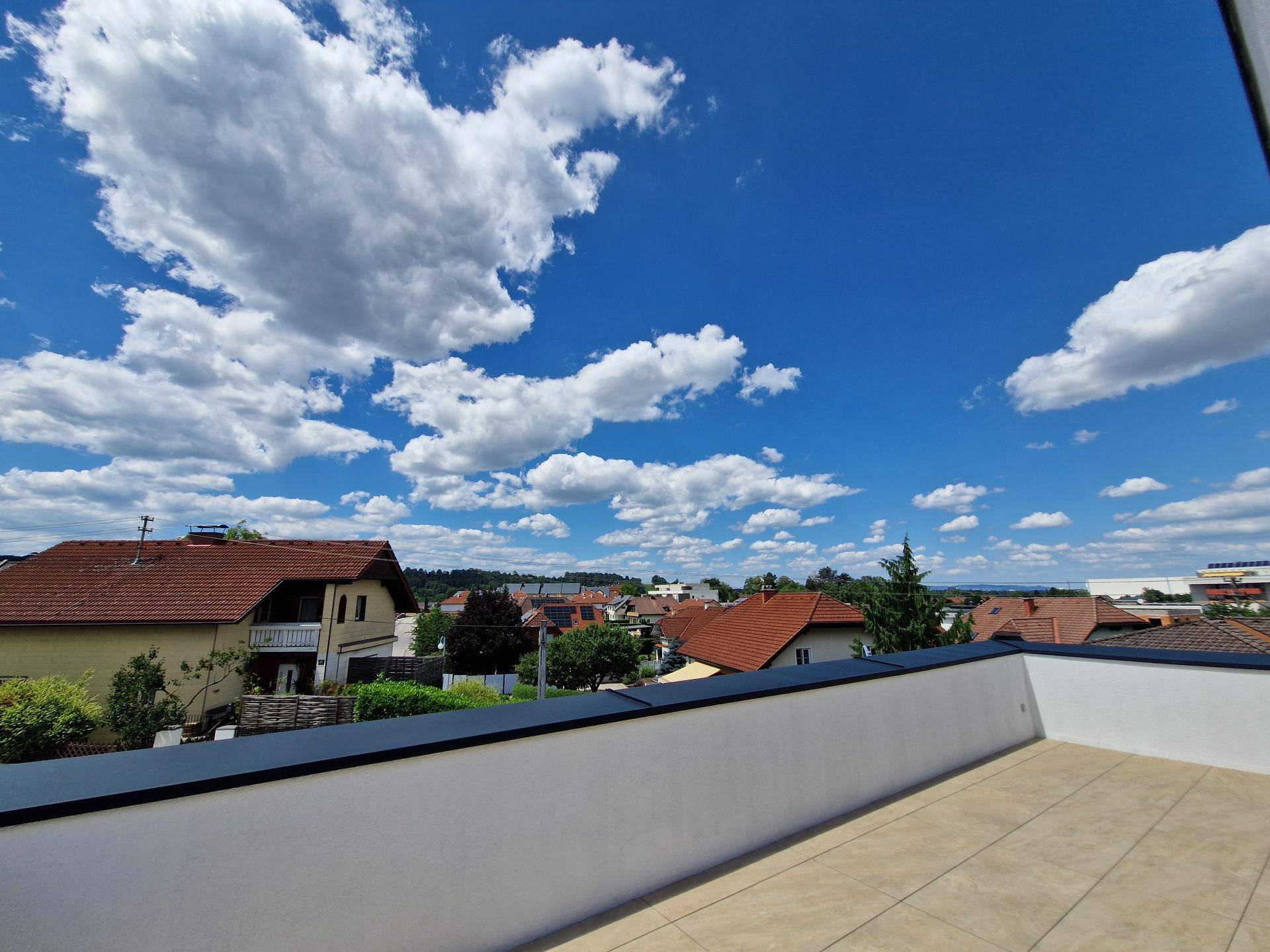 Panoramablick von der Terrasse über die Dächer der umliegenden Wohngegend unter blauem Himmel.
