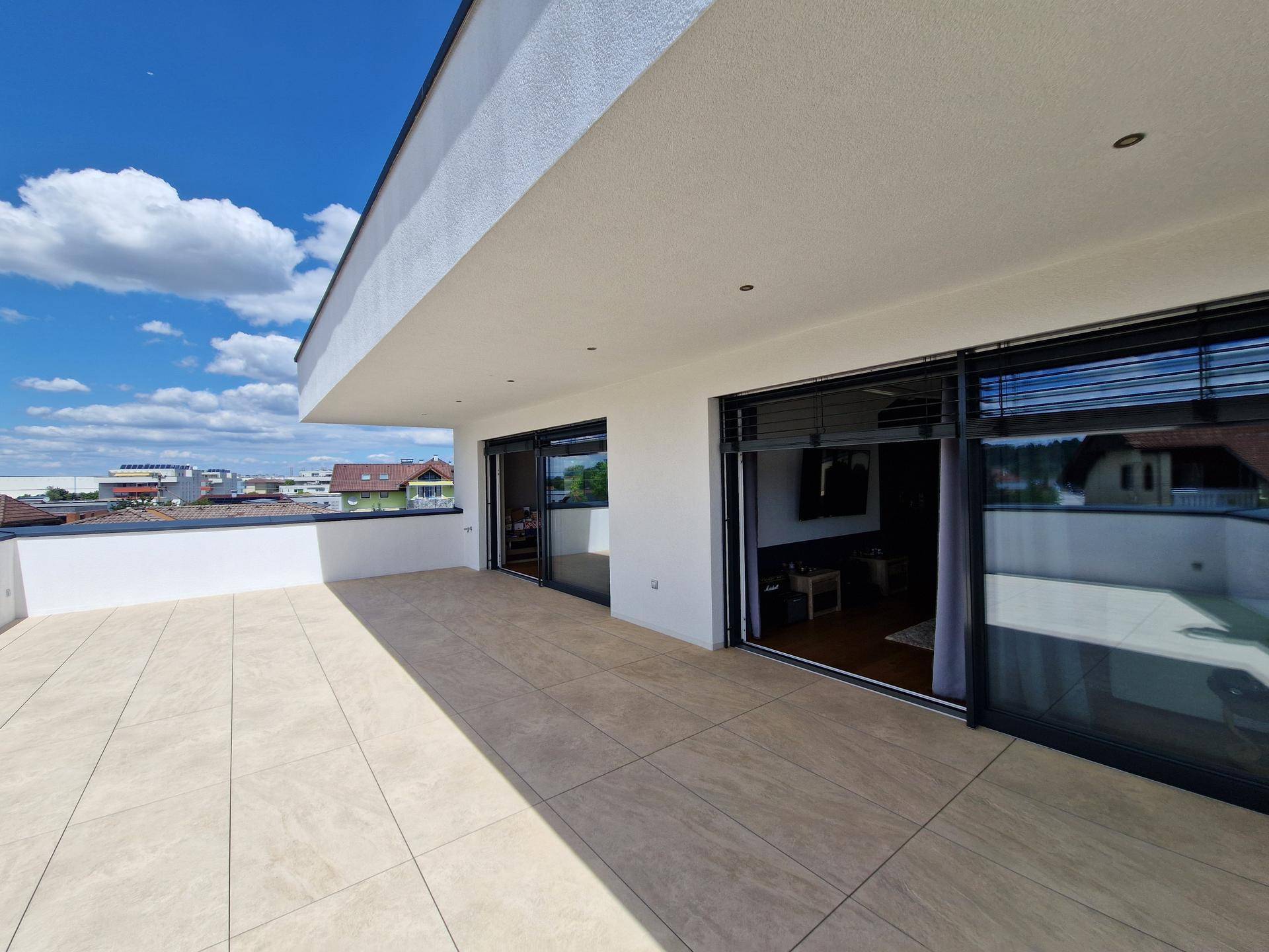 Weitläufige, geflieste Terrasse mit moderner Architektur und mehreren Zugängen zu den Innenräumen.