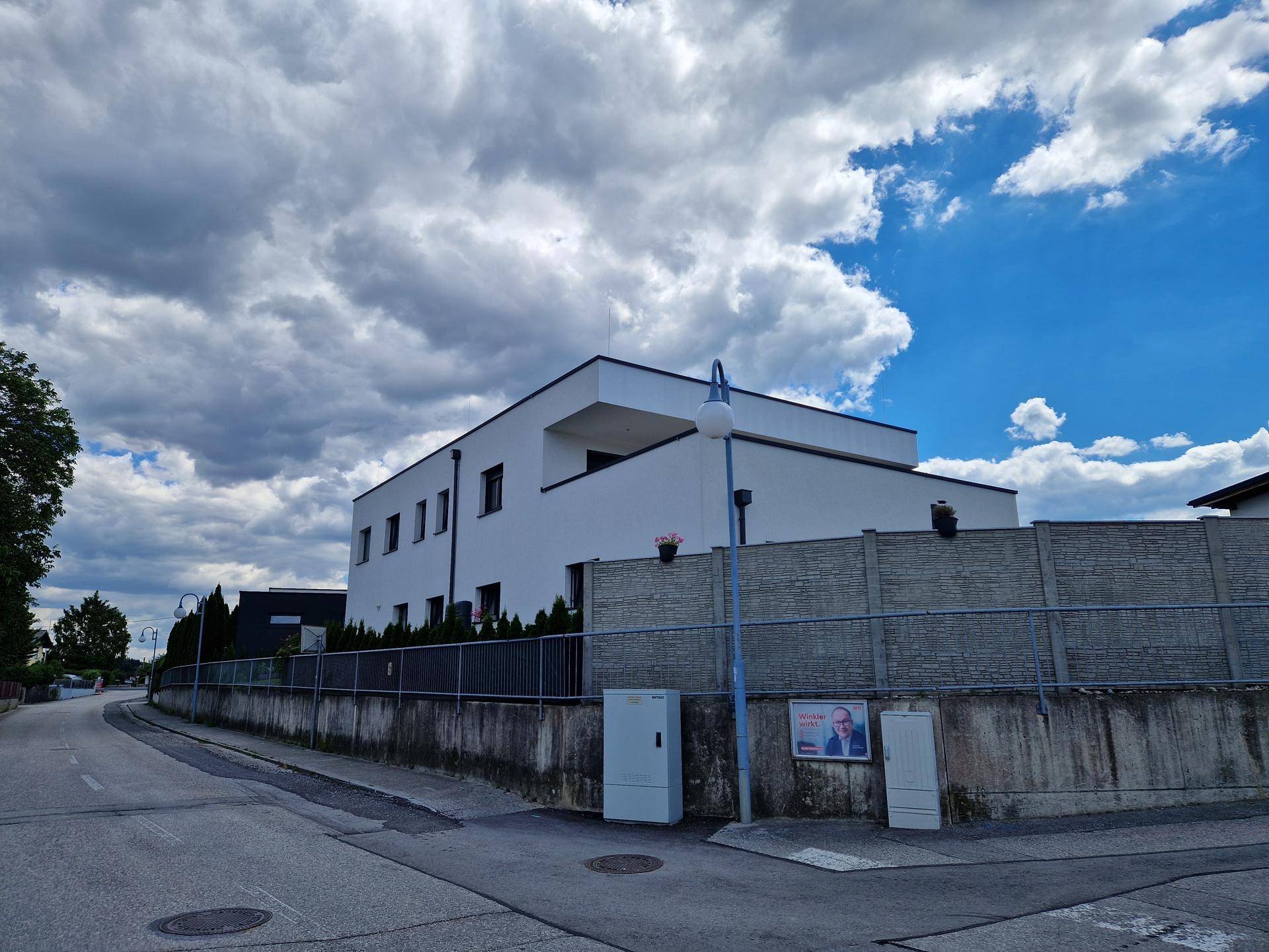 Ansicht des modernen Gebäudes von der Straße aus, umgeben von einem Betonzaun.