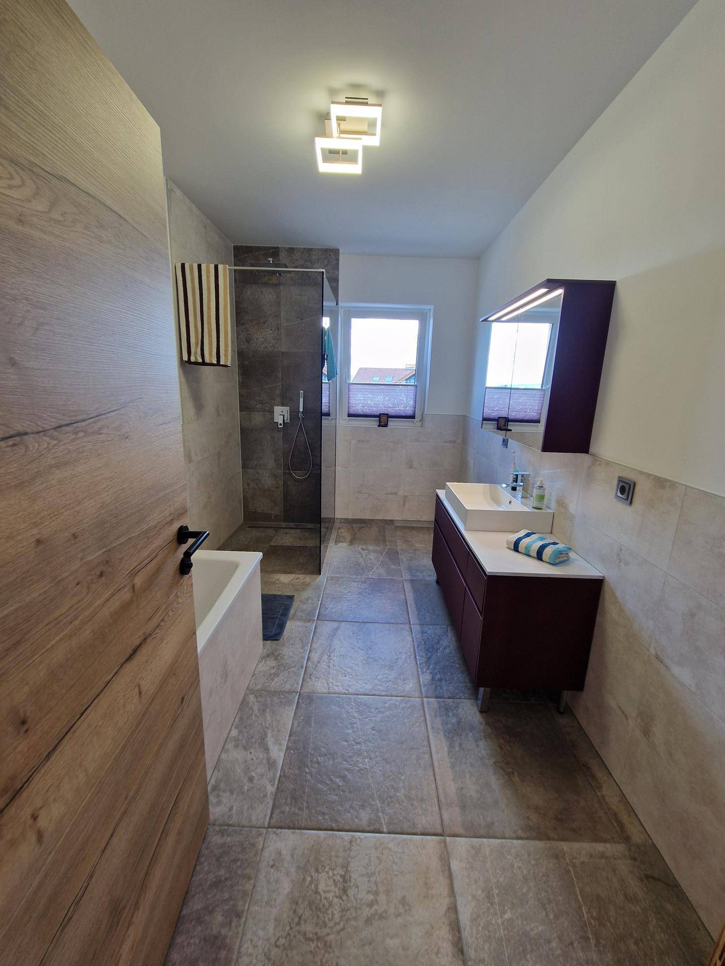 Geräumiges Badezimmer mit Badewanne, begehbarer Dusche und Doppelwaschbecken.