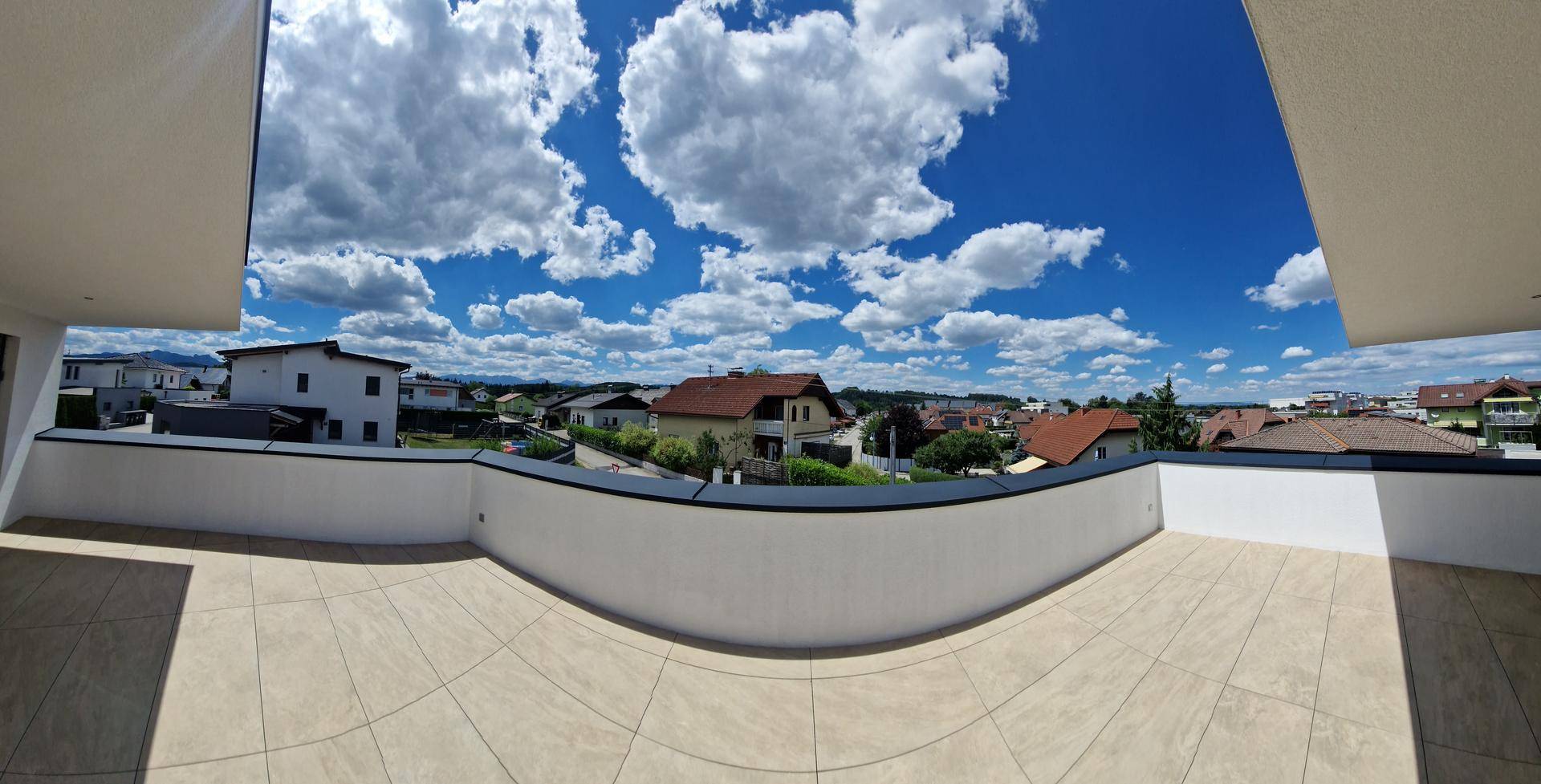 Panoramablick über die geschwungene Terrasse und die weite Landschaft mit Wohnbebauung.