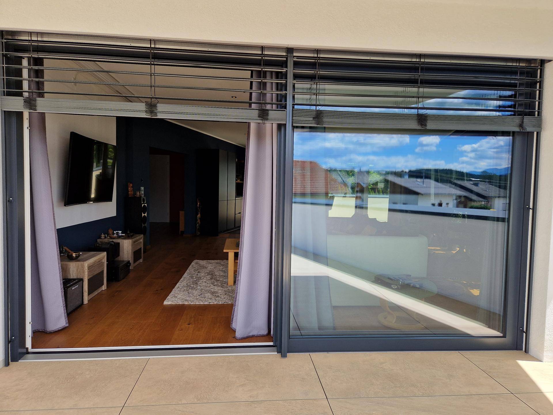 Blick von der Terrasse durch die großen Glasschiebetüren in das helle Wohnzimmer des Anwesens.