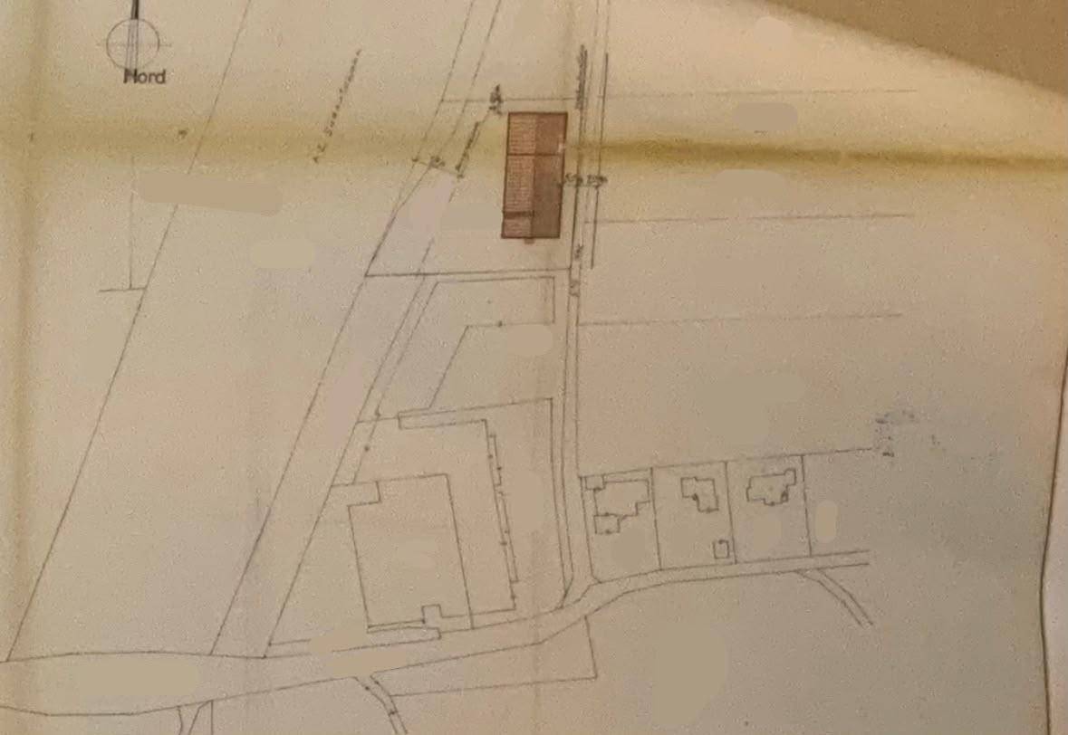 Übersichtsplan eines Grundstücks mit eingezeichneten Gebäuden und Straßenverlauf in ländlicher Umgebung.