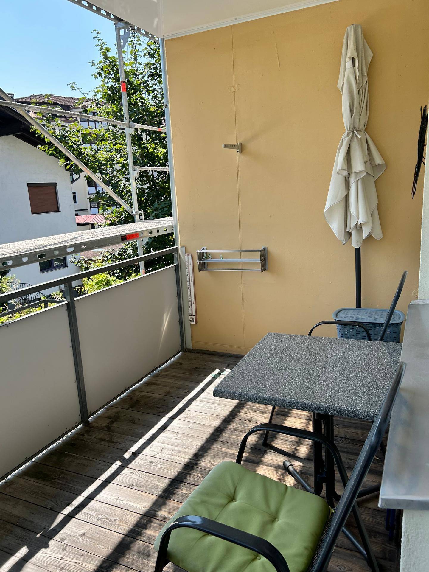 Heller Balkon mit Holzboden und Blick auf die Umgebung, ideal für Mahlzeiten im Freien.