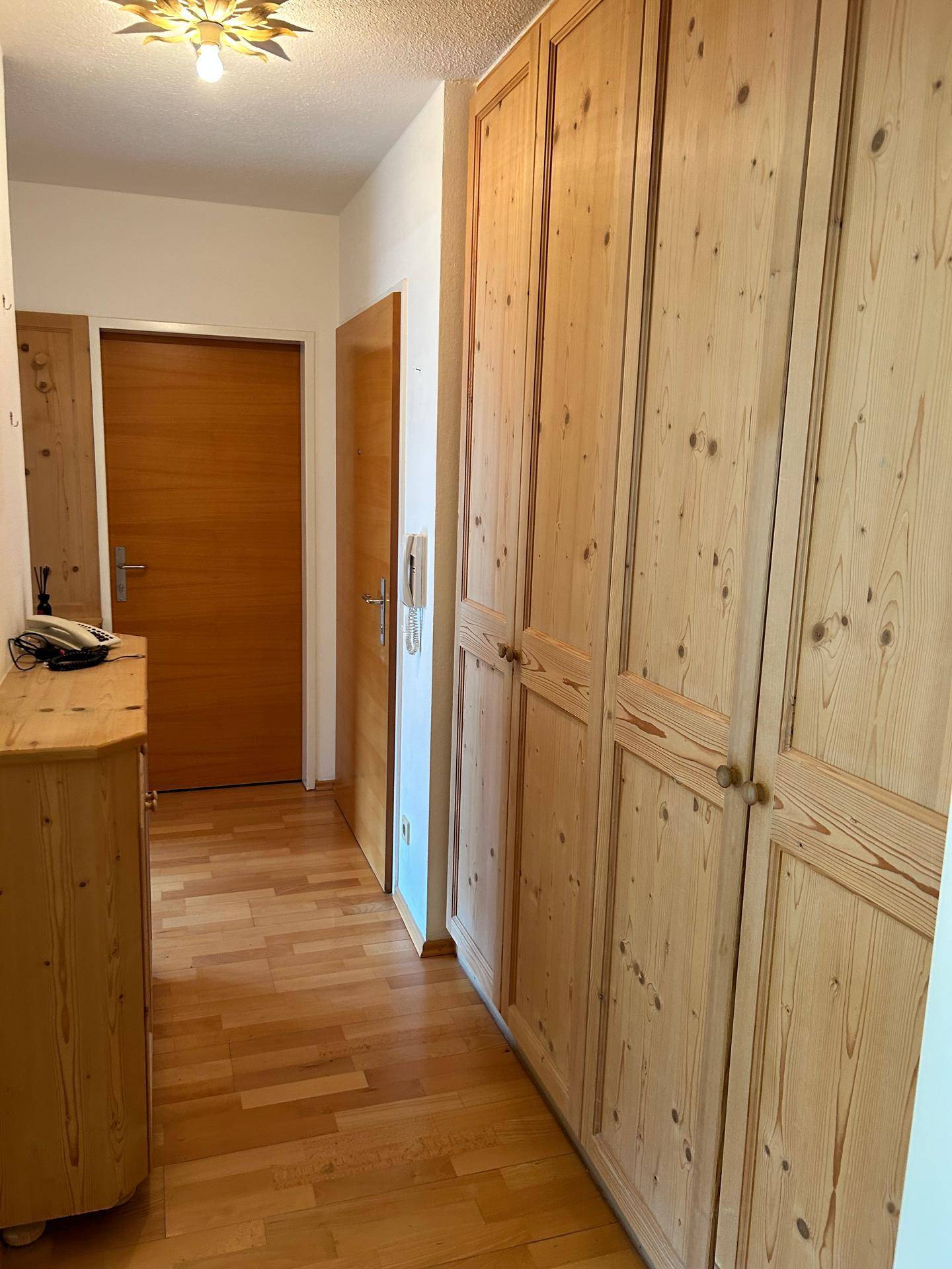 Flur mit praktischen Einbauschränken aus Holz und einer Kommode für zusätzlichen Stauraum.