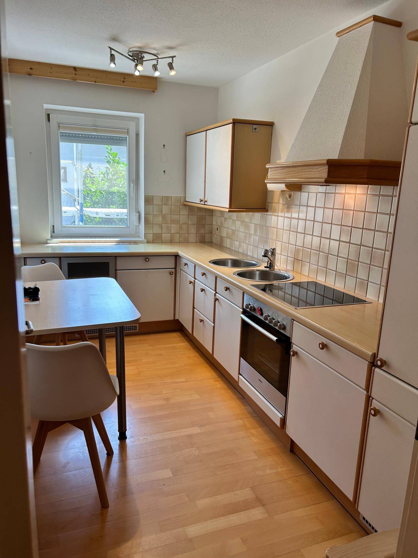 Helle Einbauküche mit Essbereich, Fenster und ausreichend Stauraum in den Schränken.