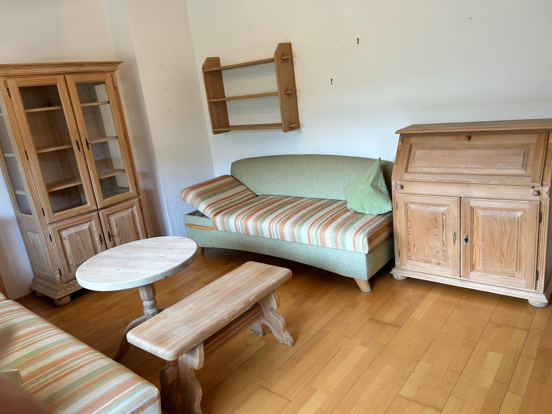 Wohnbereich mit rustikalen Holzmöbeln, bequemer Couch und einfacher Wanddekoration.