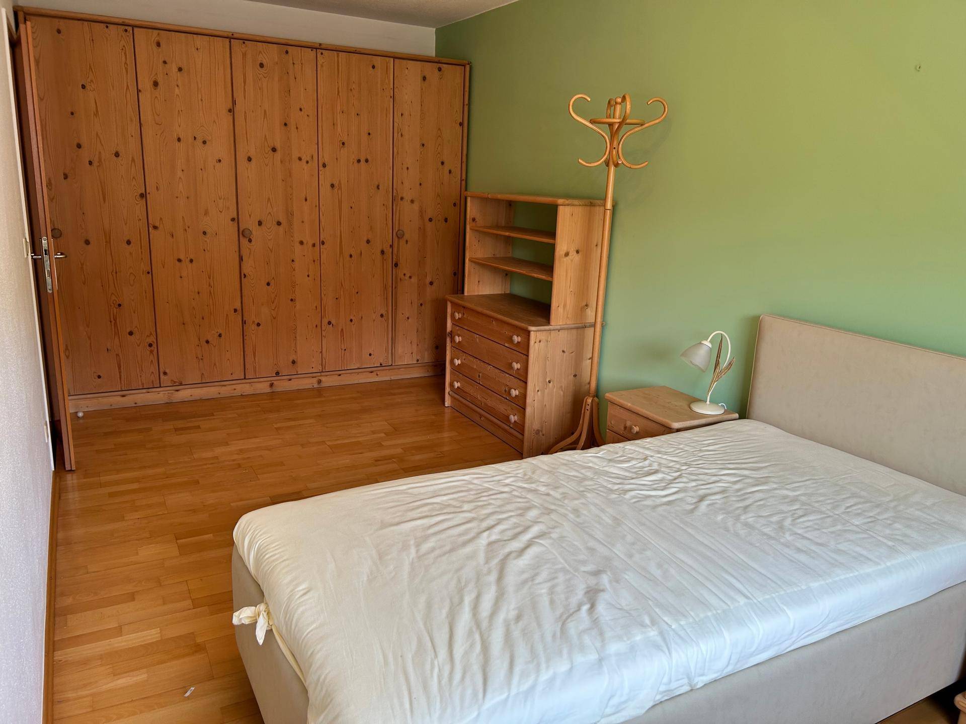 Geräumiges Schlafzimmer mit großem Einbauschrank aus Holz und Einzelbett.