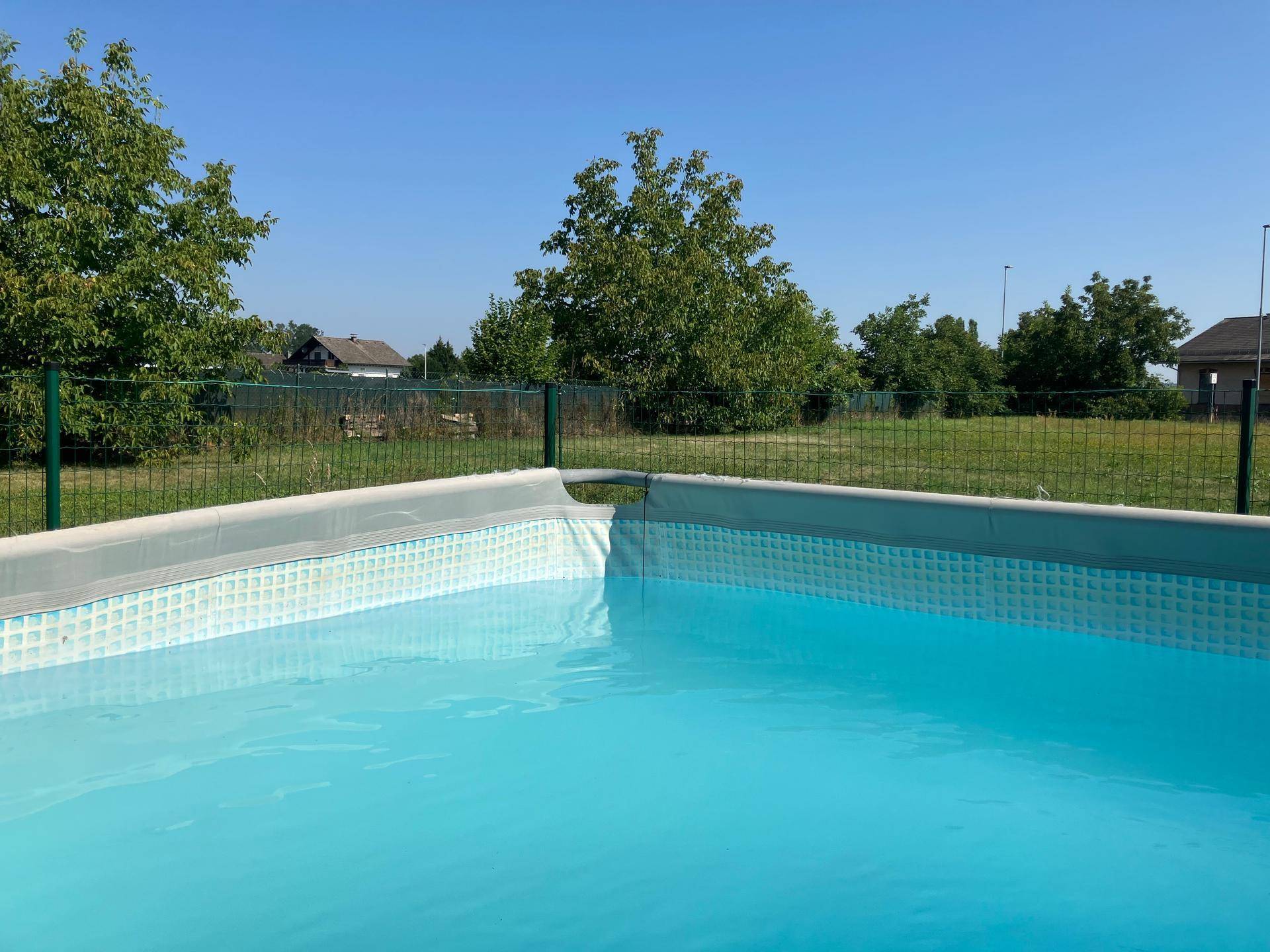 Aufstellpool mit klarem Wasser in einem sonnigen Gartenbereich mit grüner Umgebung.