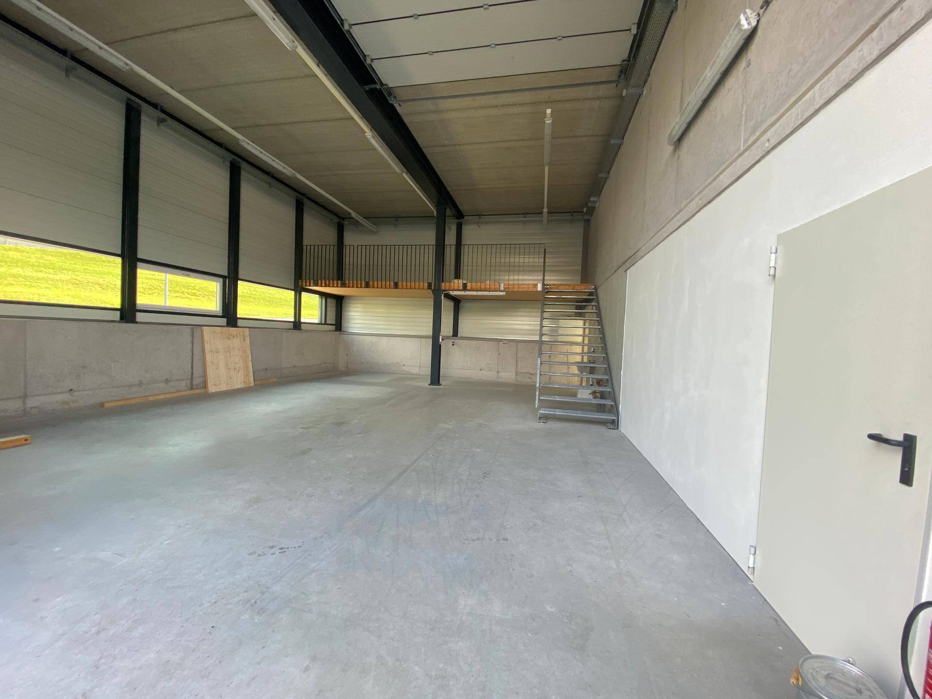 Großer, leerer Lagerraum mit hoher Decke, Betonboden und einer Stahlkonstruktion für eine Empore.