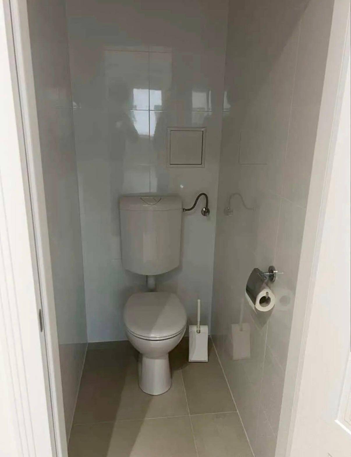 Kleines, gefliestes WC mit Toilette und Spülkasten, in einem sauberen und funktionalen Zustand.