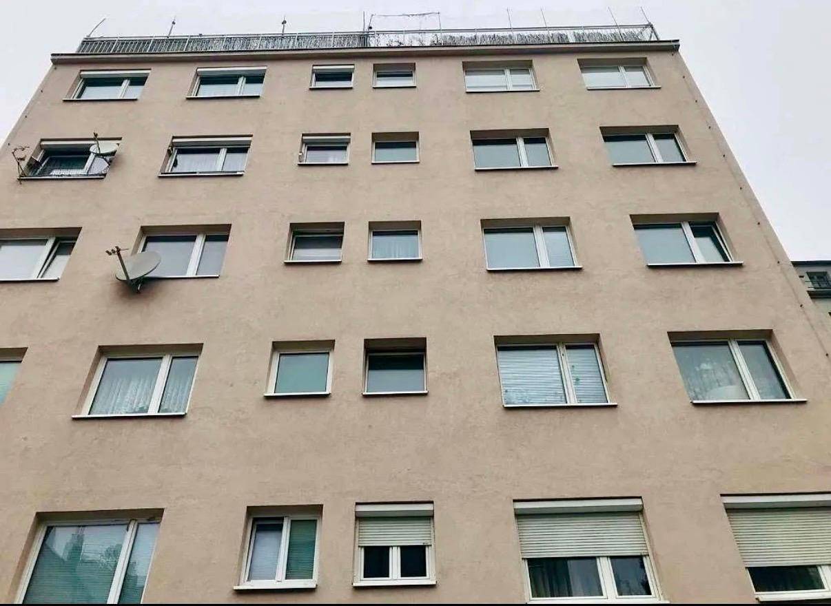 Fassade eines modernen Mehrfamilienhauses mit zahlreichen Fenstern, Balkonen und Rollläden.