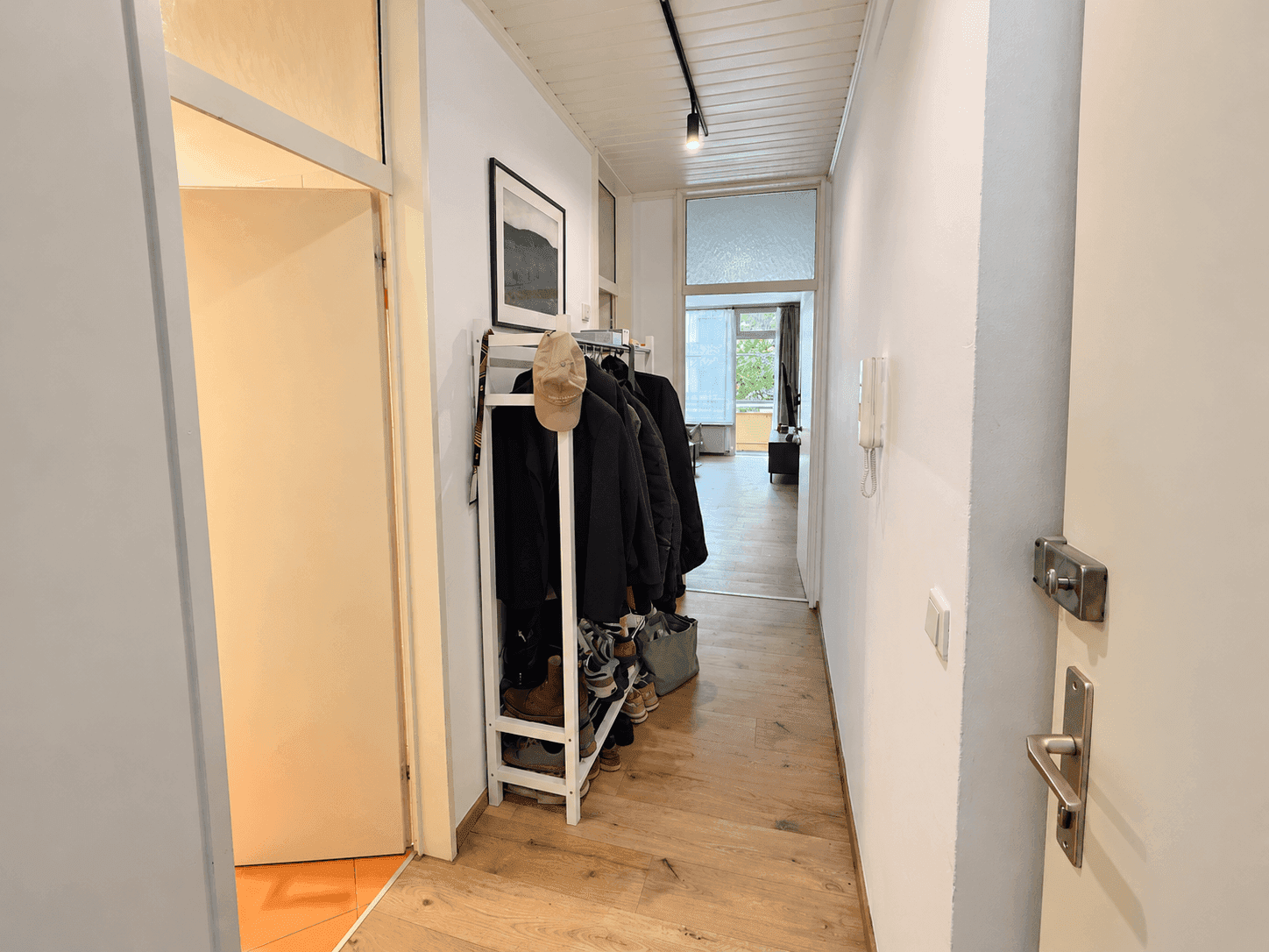 Heller Flur mit Garderobe, Holzdecke und Parkettboden, der zu weiteren Räumen führt.