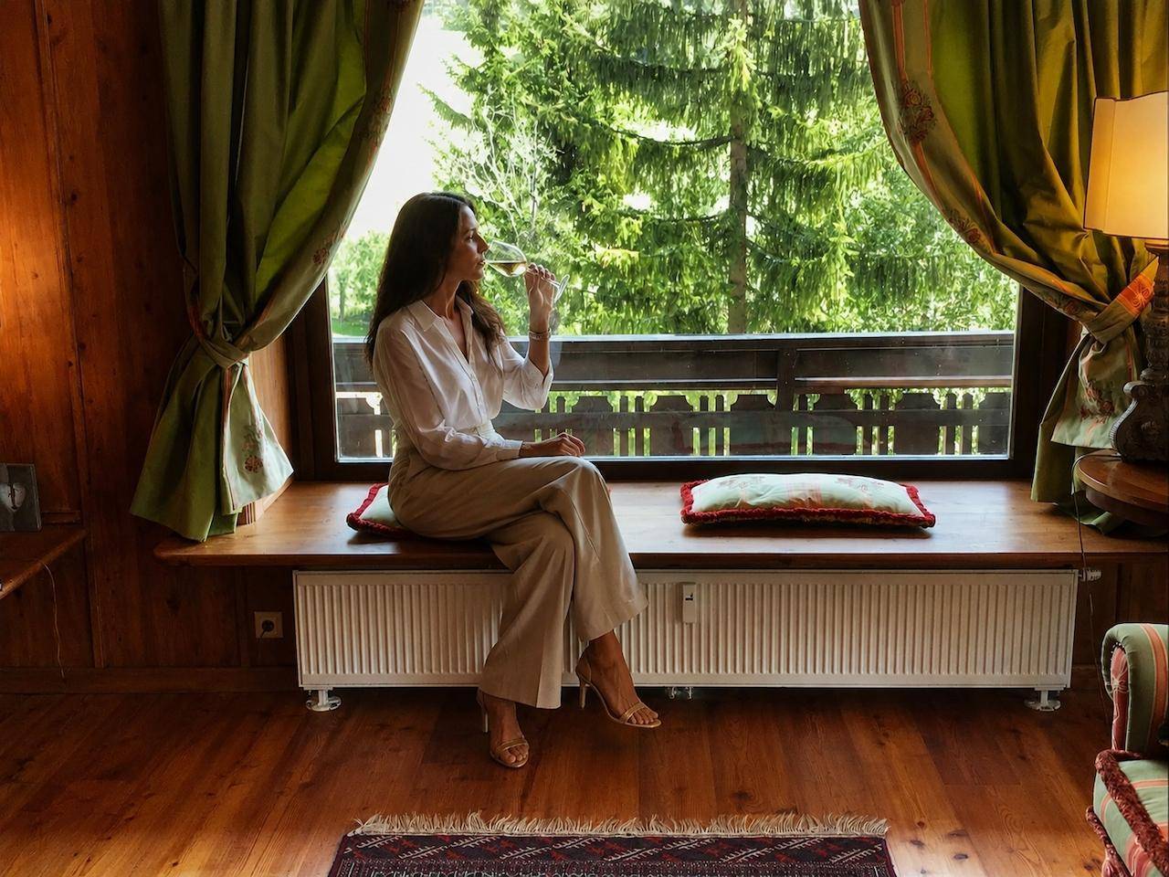 Frau genießt den Ausblick aus dem Wohnzimmerfenster mit Blick auf die umliegende Natur.
