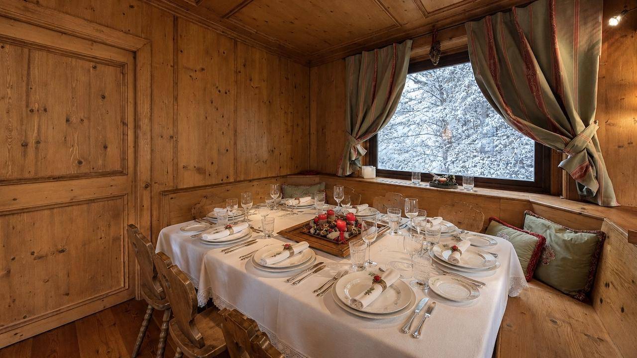 Rustikaler Essbereich mit Holztäfelung, festlich gedecktem Tisch und winterlichem Ausblick.