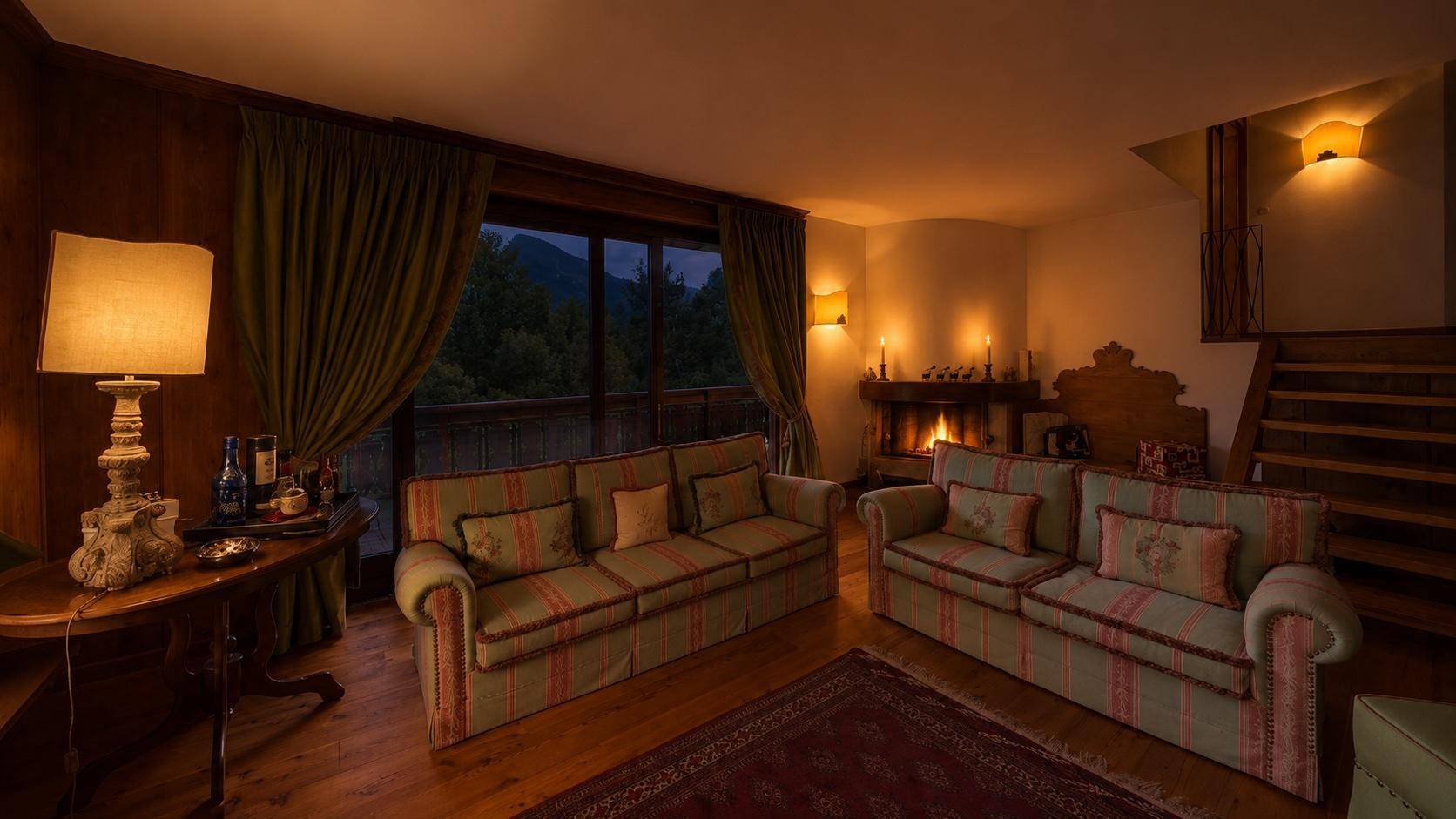 Abendliche Atmosphäre im Wohnzimmer mit knisterndem Kaminfeuer und Blick auf die Berge.