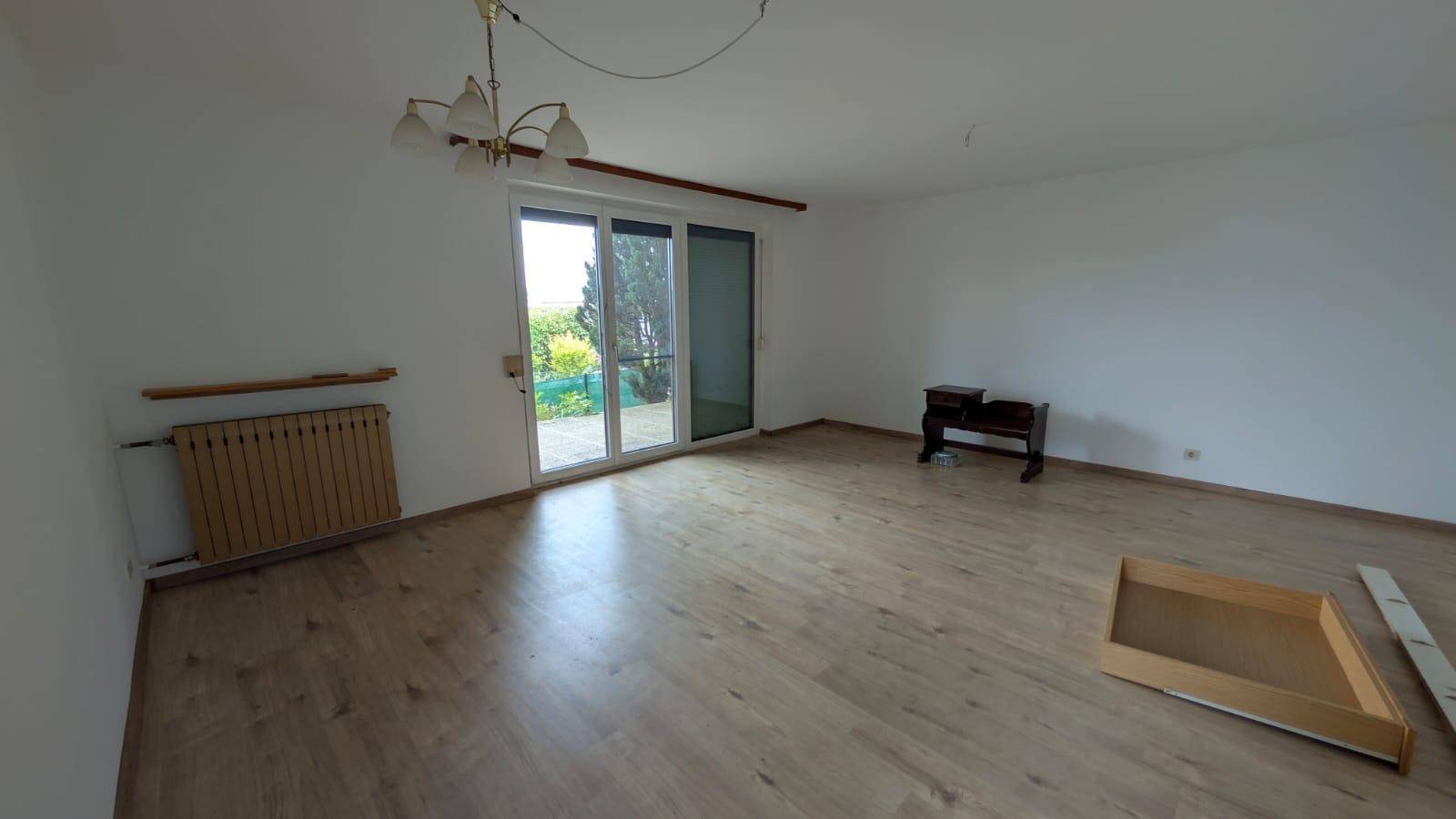 Geräumiges Wohnzimmer mit Laminatboden und großen Schiebetüren zum Außenbereich.
