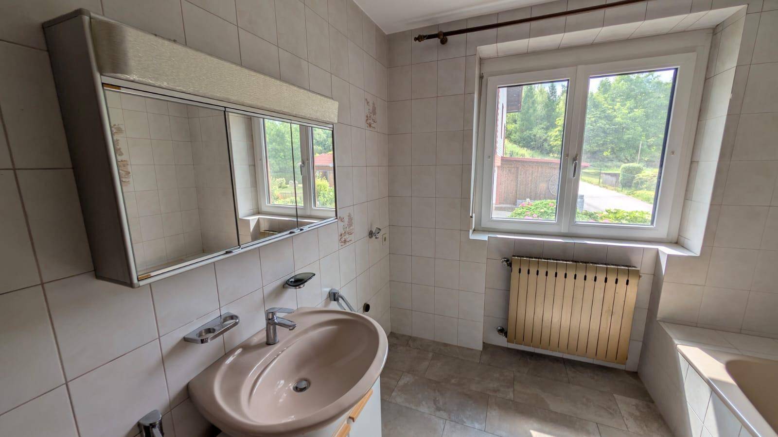 Badezimmer mit Waschbecken, Spiegelschrank und Fenster, gefliest in einem traditionellen Stil.