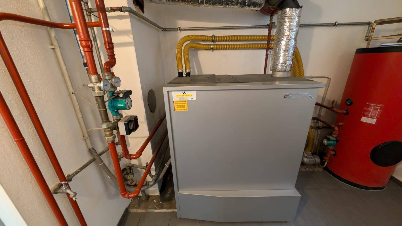 Gut gewarteter Heizkessel und Warmwasserspeicher in einem sauberen Technikraum.