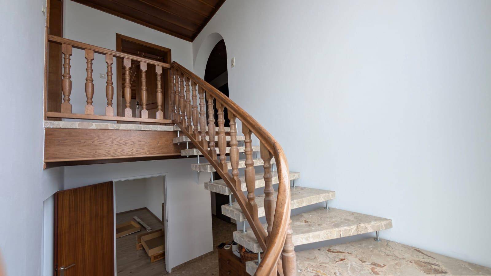 Elegante Holztreppe mit Steinstufen, die die verschiedenen Ebenen des Hauses verbindet.