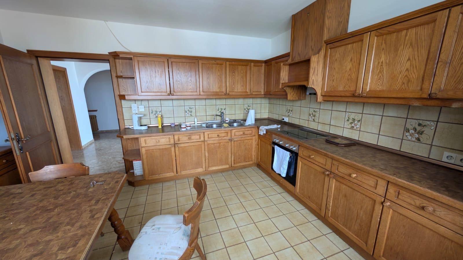 Traditionelle Holzküche mit Einbauschränken, Fliesenboden und integrierten Geräten.