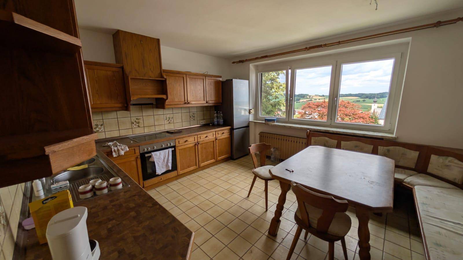 Gemütliche Wohnküche mit Holzeinrichtung, Essbereich und großem Fenster mit Ausblick.