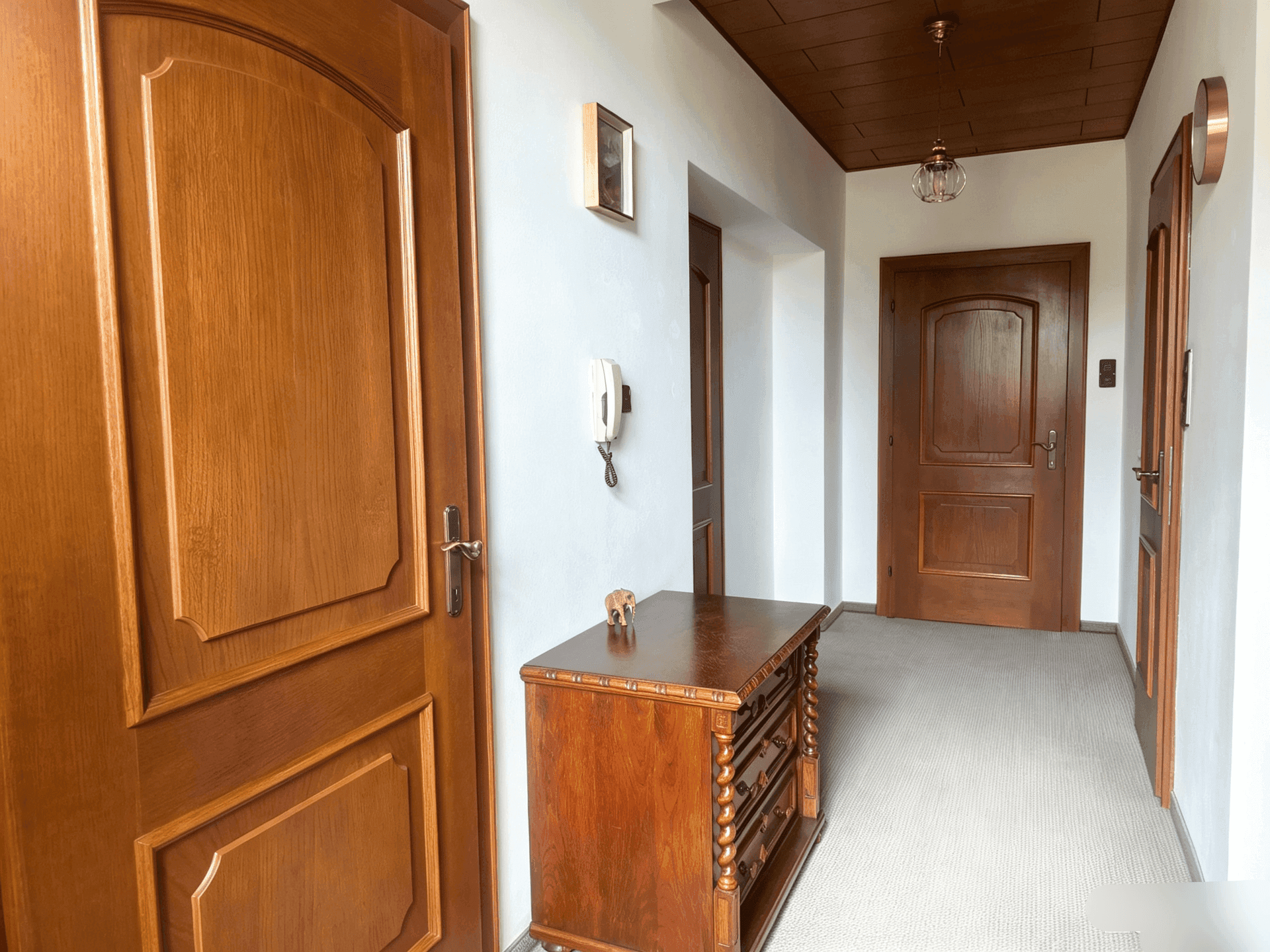 Gemütlicher Flur mit Holztüren, Holzdecke und einem antiken Holzschrank.