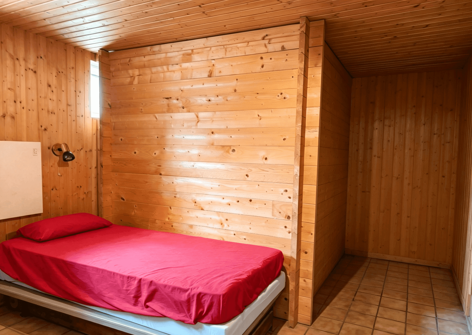 Gemütliches Schlafzimmer mit Holzvertäfelung und Einzelbett.
