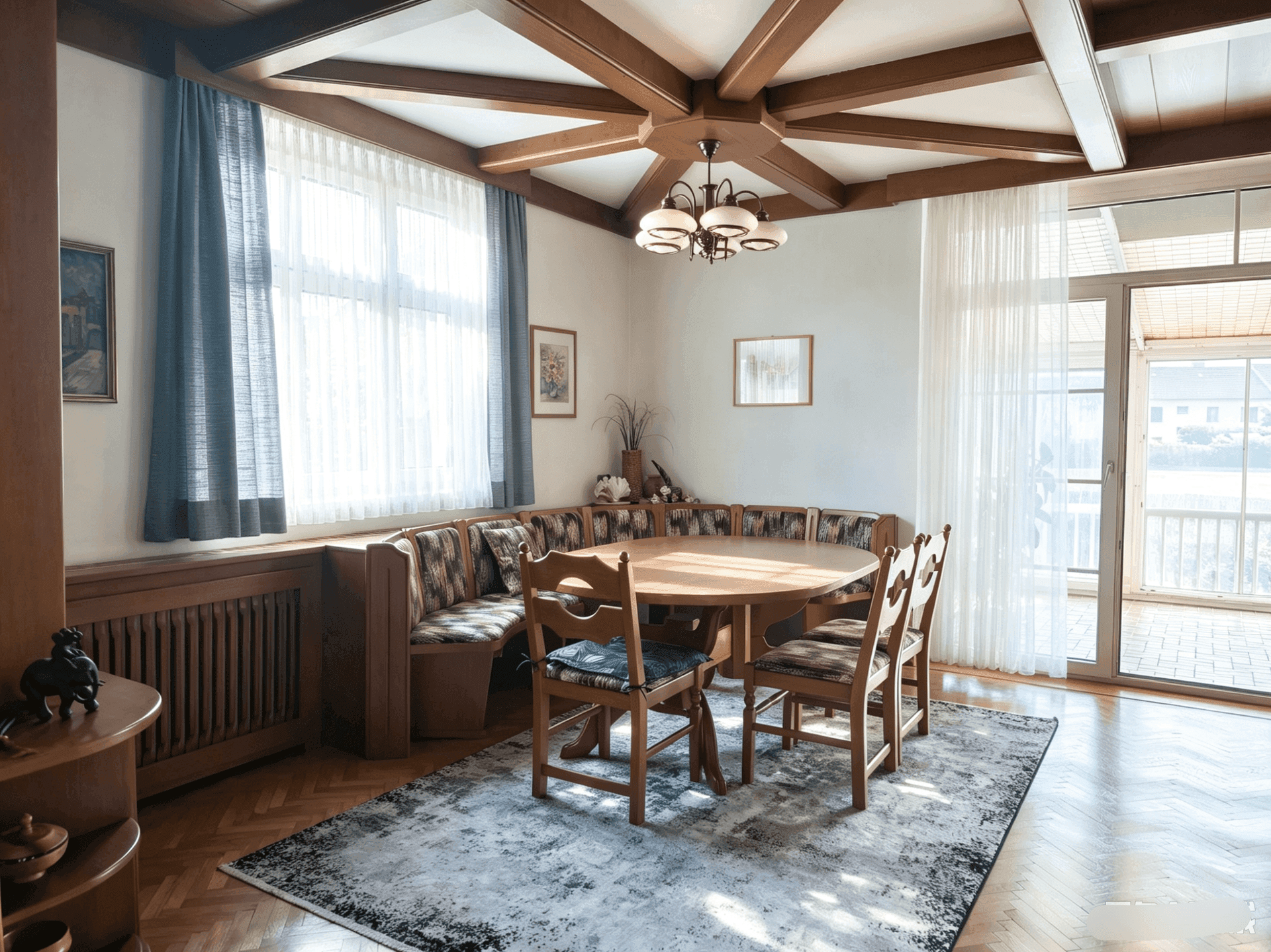 Heller Essbereich mit rundem Holztisch, Eckbank und Zugang zum Wintergarten.