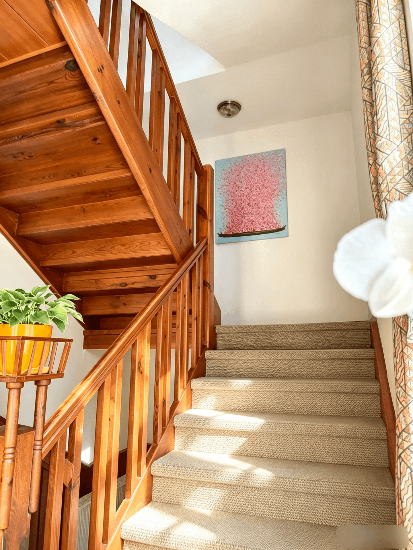 Helles Treppenhaus mit Holzgeländer, Teppichstufen und einem farbenfrohen Kunstwerk an der Wand.