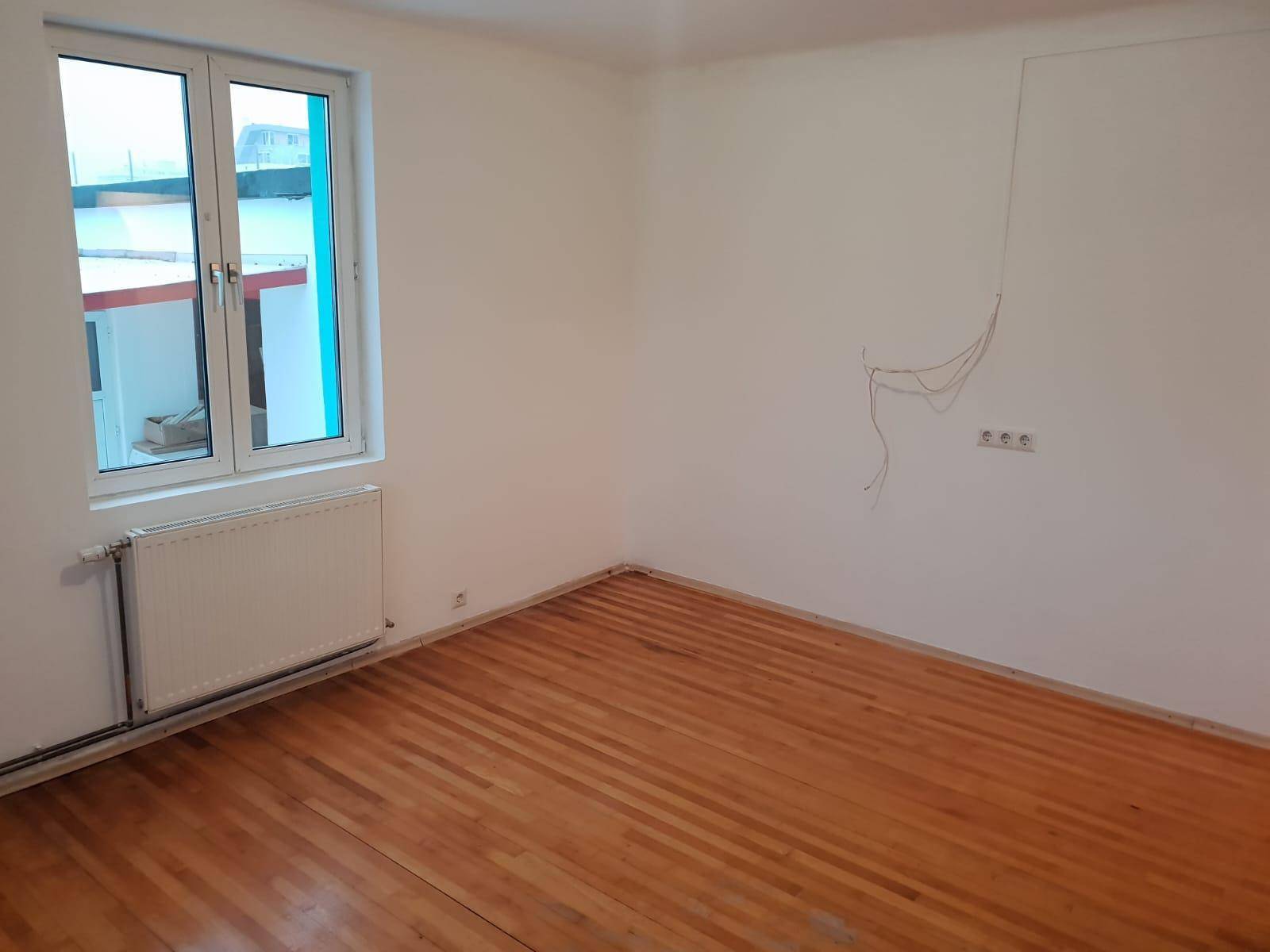 Unmöblierter Raum mit Holzboden und einem Fenster, bereit für die Endmontage.