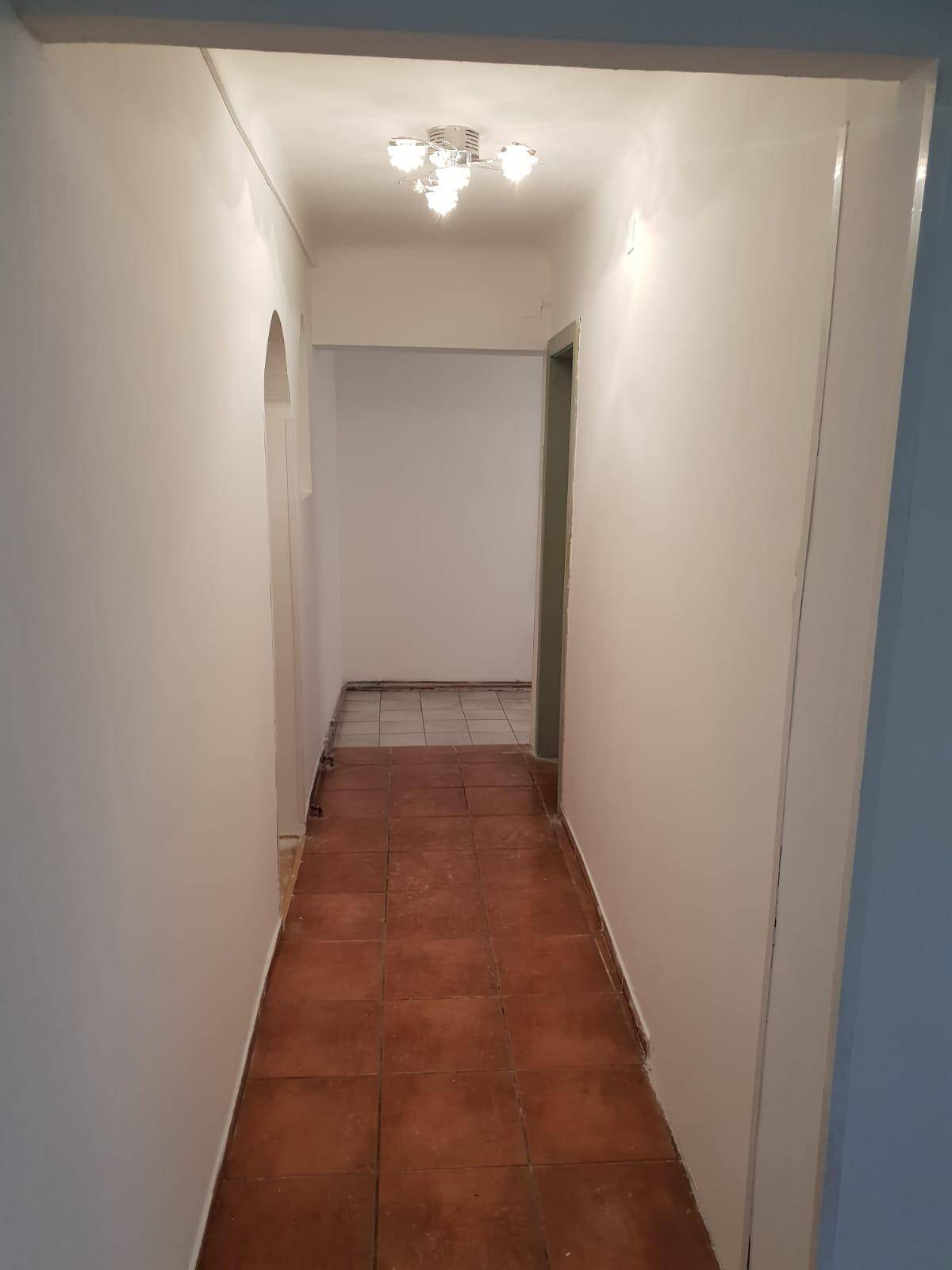 Heller Flur mit Terrakotta-Fliesen und einem modernen Deckenlicht.