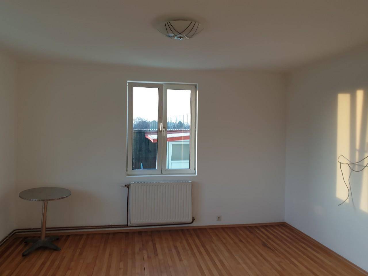 Heller Raum mit Holzboden und einem Fenster, ideal für ein Schlaf- oder Wohnzimmer.