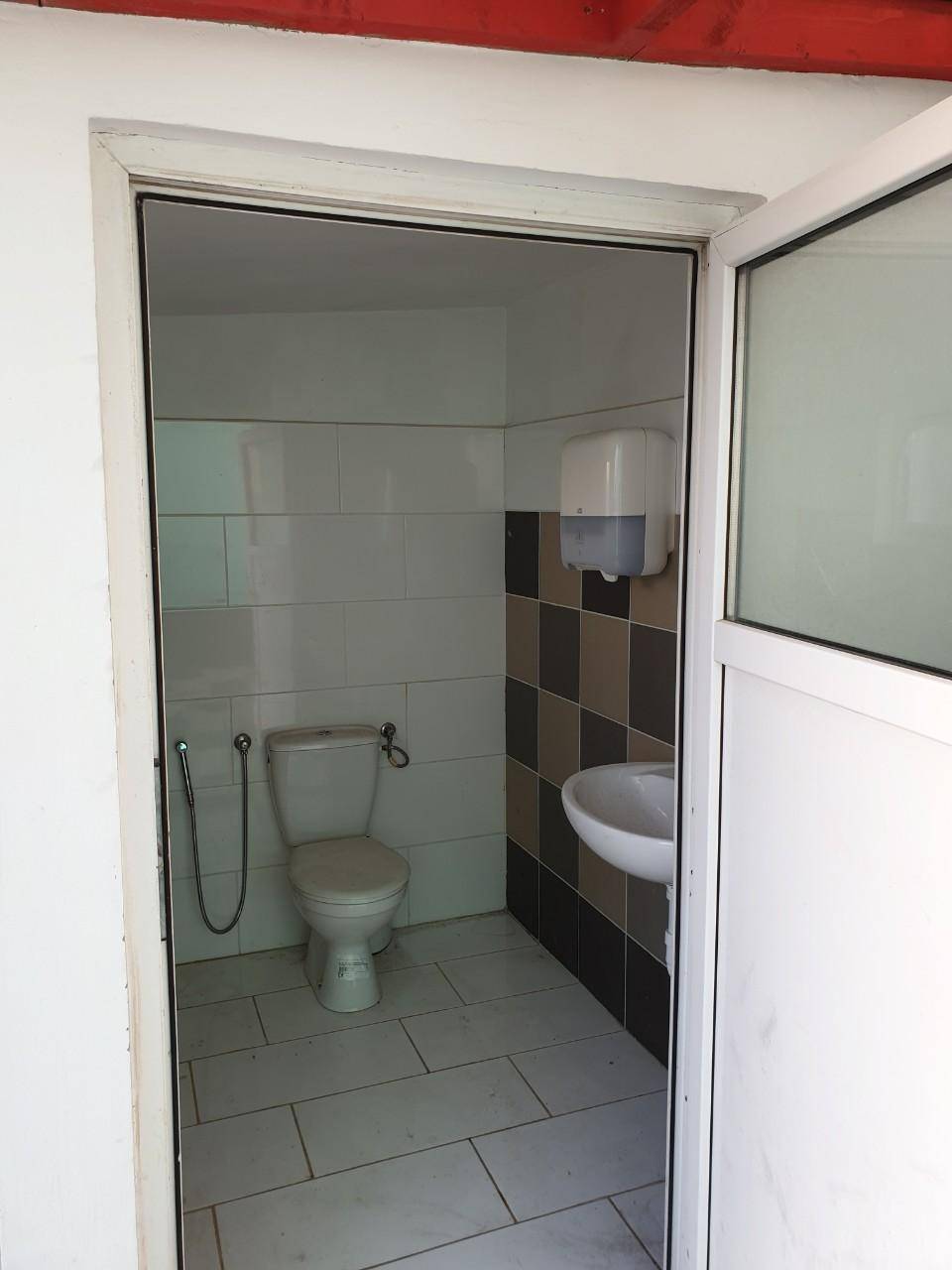Kleines WC mit Fliesen an den Wänden, Toilette und einem Handwaschbecken.