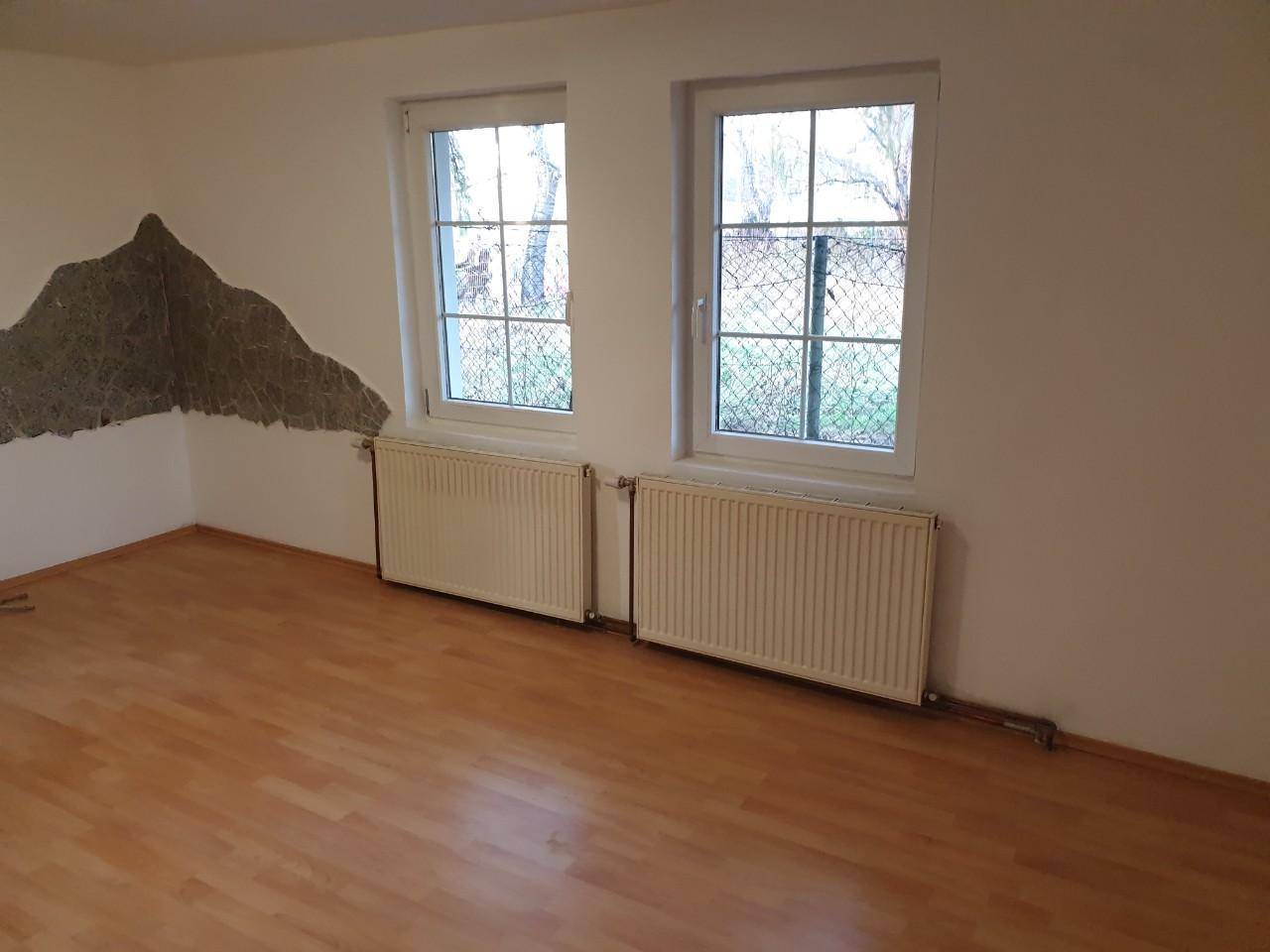 Geräumiger Raum mit Holzboden und zwei Fenstern, bietet viel Tageslicht.