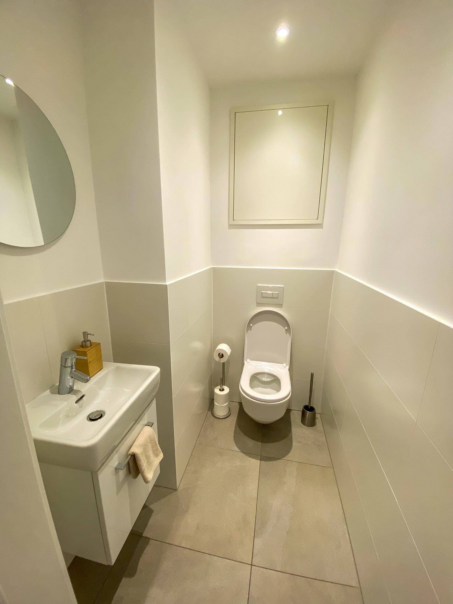 Kleines Gäste-WC mit modernem Waschbecken, Toilette und Fliesenboden.