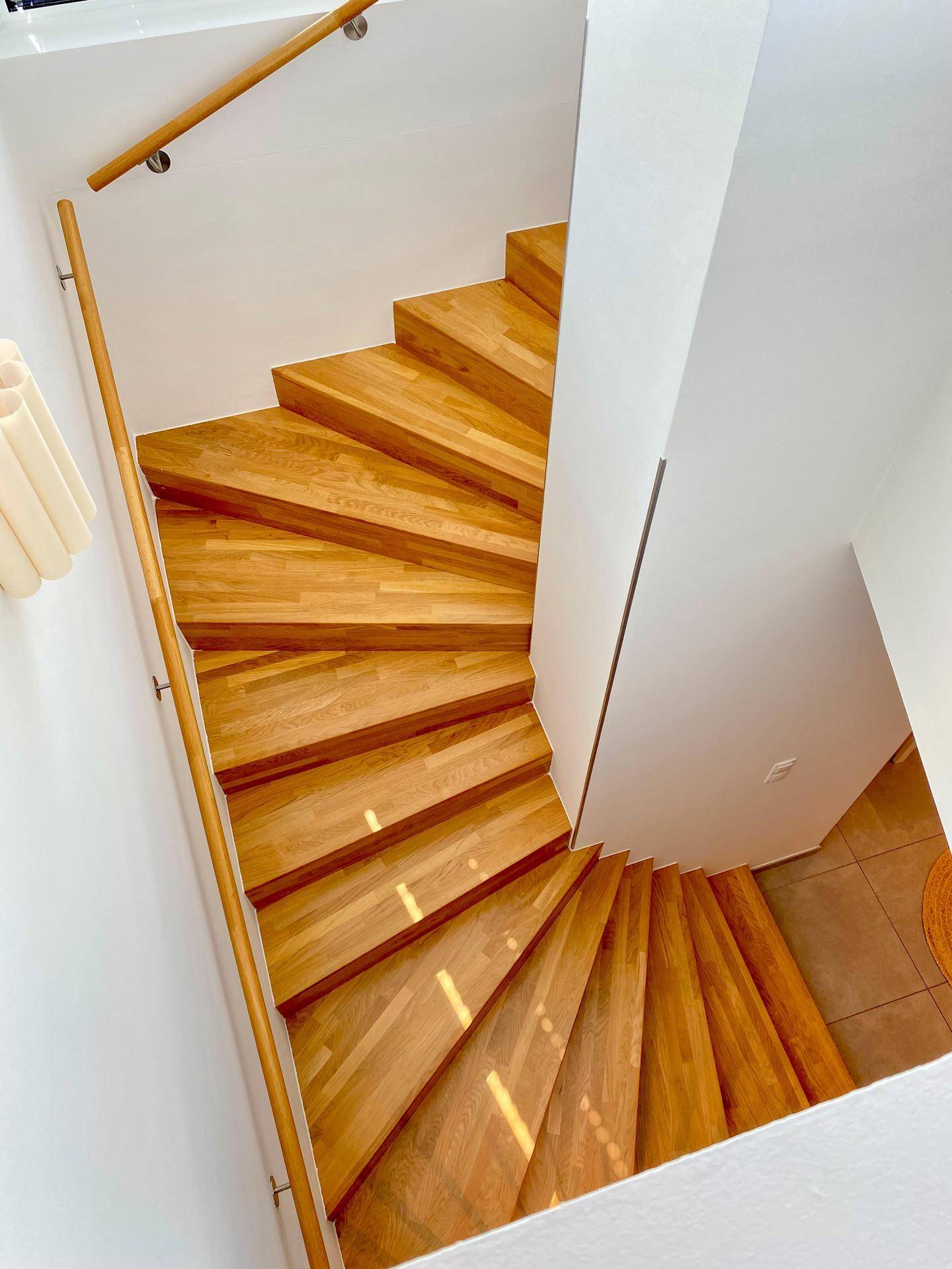 Elegante Holztreppe mit Handlauf verbindet die verschiedenen Ebenen der Wohnung.