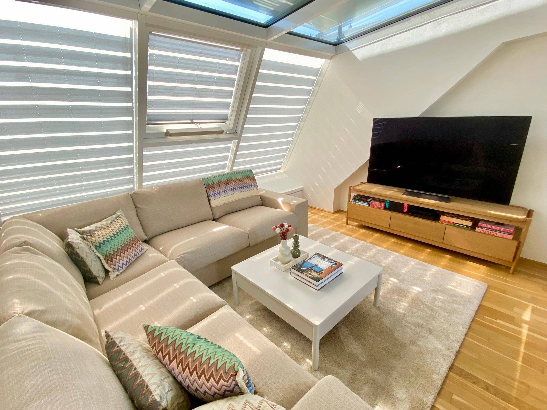 Helles Wohnzimmer mit großem Ecksofa, Holzboden, modernen Möbeln und Dachfenstern für viel Tageslicht.